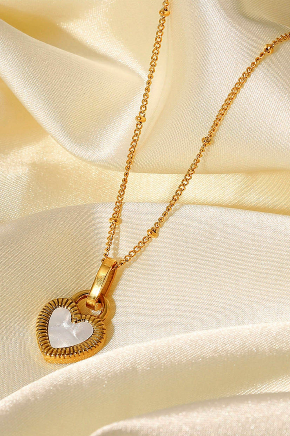 A stylish Contrast Heart Pendant Necklace featuring a heart-shaped pendant on a stainless steel chain, elegantly displayed in a flat lay style.