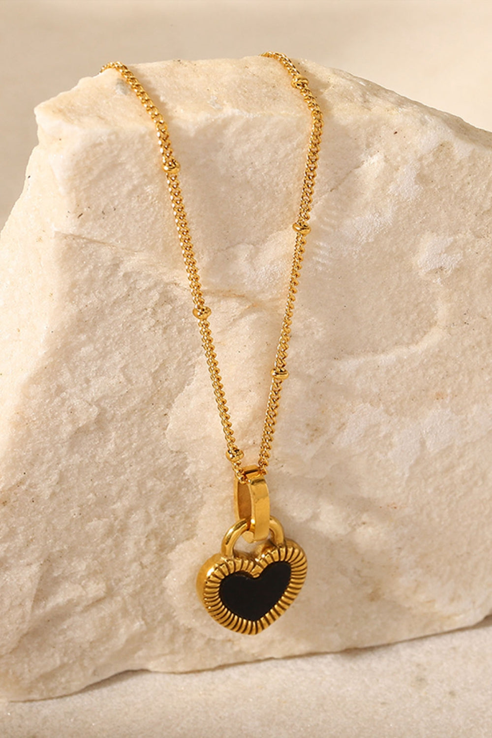 A stylish Contrast Heart Pendant Necklace featuring a heart-shaped pendant on a stainless steel chain, elegantly displayed in a flat lay style.