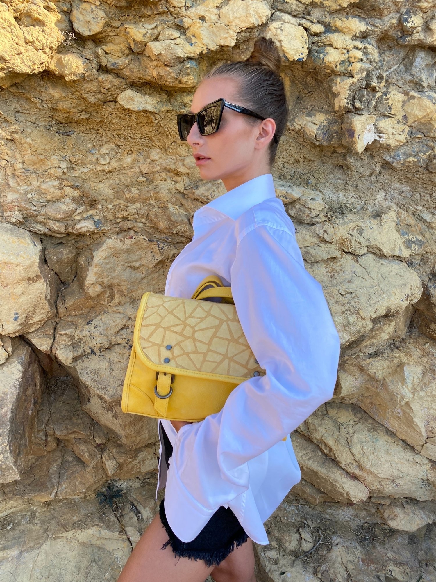 Stylish yellow crossbody bag with buckle and adjustable strap, featuring metallic details and a lined interior.