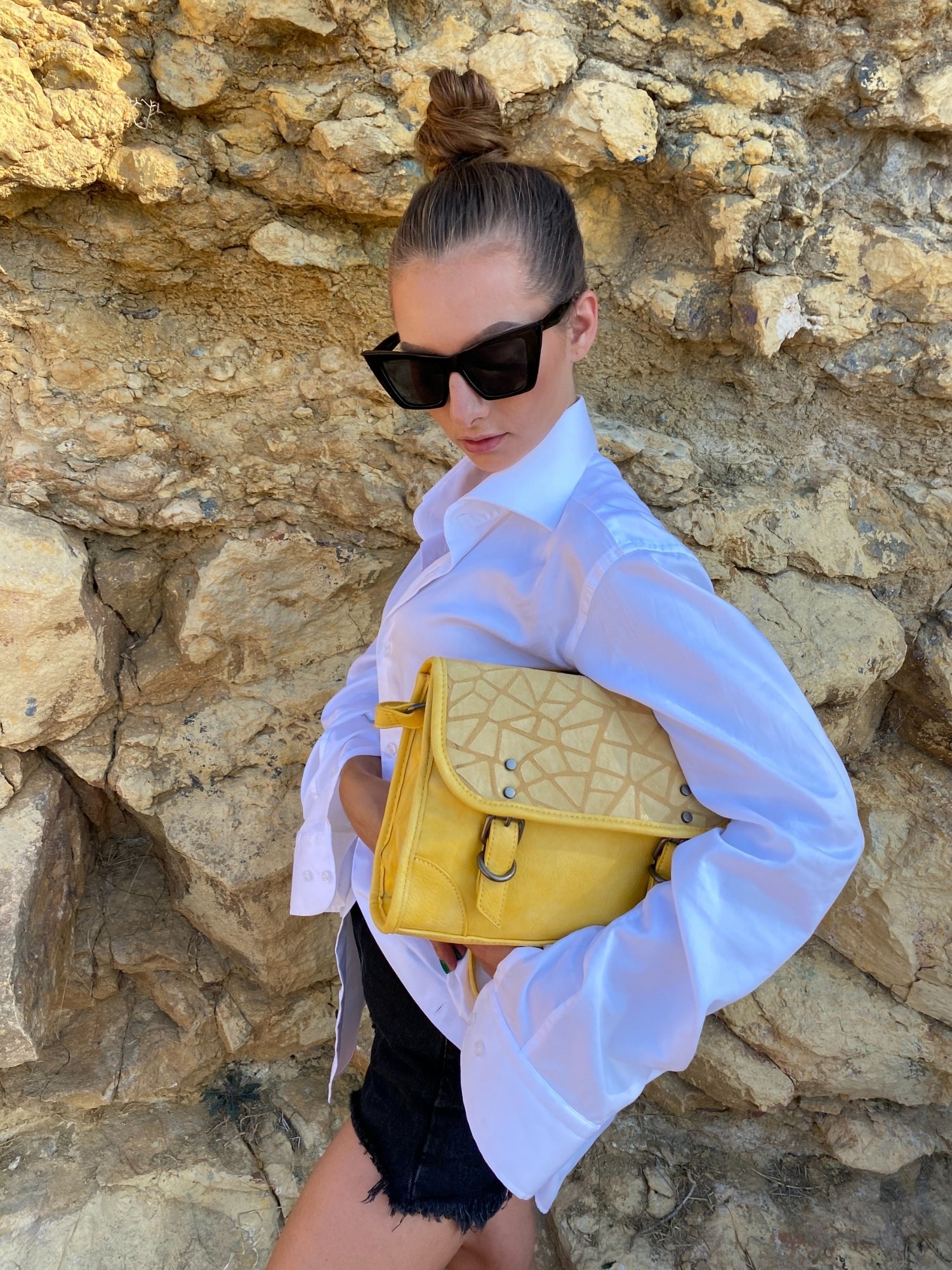 Stylish yellow crossbody bag with buckle and adjustable strap, featuring metallic details and a lined interior.