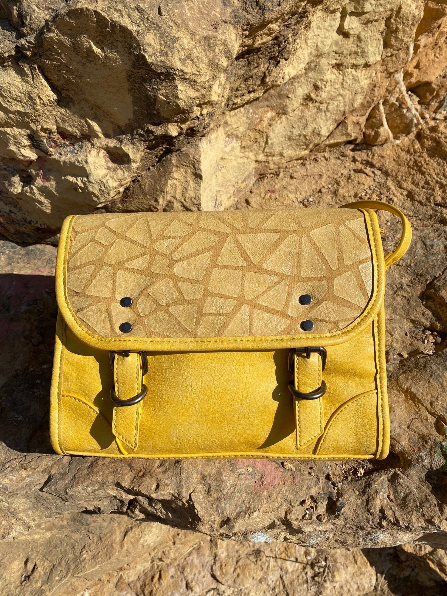 Stylish yellow crossbody bag with buckle and adjustable strap, featuring metallic details and a lined interior.