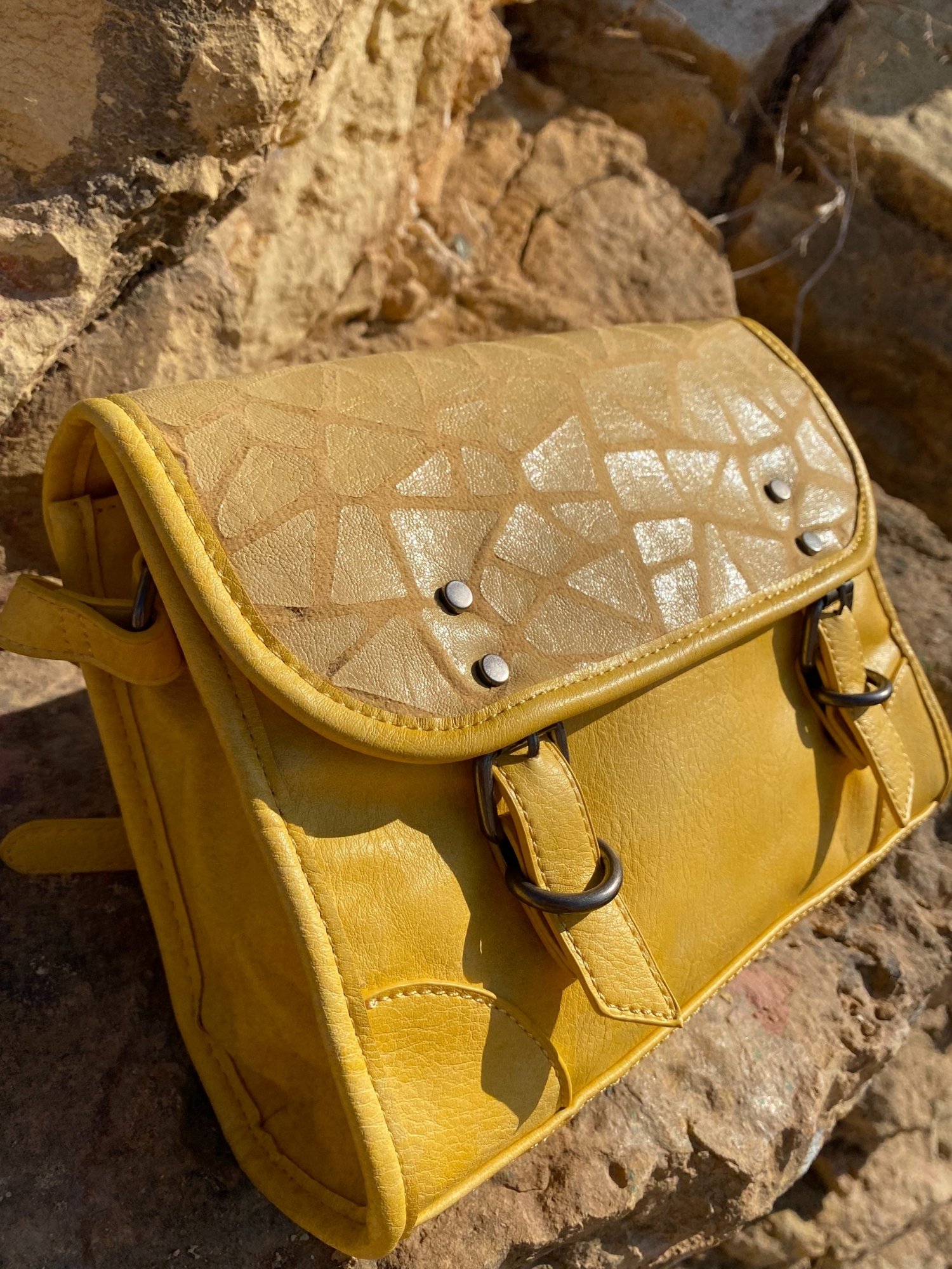 Stylish yellow crossbody bag with buckle and adjustable strap, featuring metallic details and a lined interior.