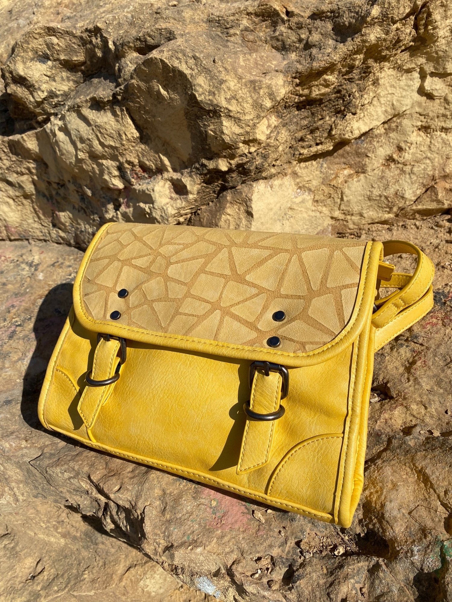 Stylish yellow crossbody bag with buckle and adjustable strap, featuring metallic details and a lined interior.