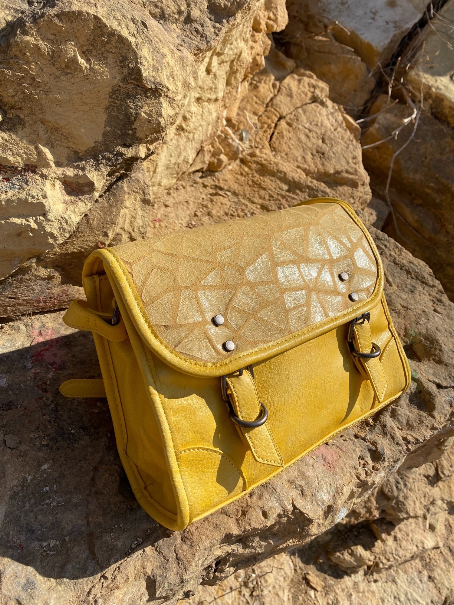 Stylish yellow crossbody bag with buckle and adjustable strap, featuring metallic details and a lined interior.