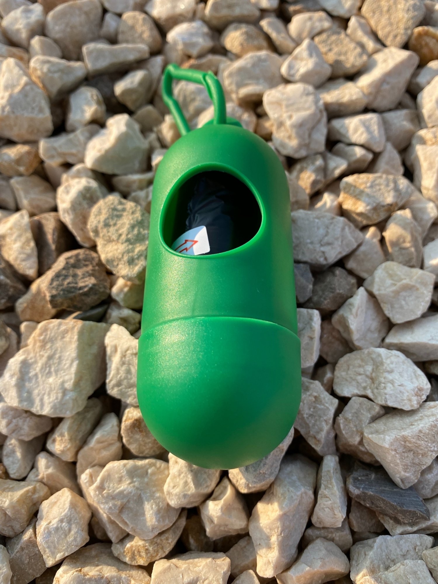 Dog Poop Bag Dispenser in Blue, Red, and Green colors with bags attached, showcasing its carabiner clip and easy-access slot.