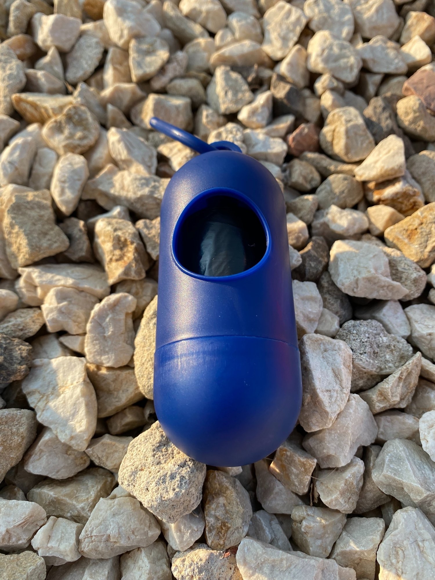 Dog Poop Bag Dispenser in Blue, Red, and Green colors with bags attached, showcasing its carabiner clip and easy-access slot.