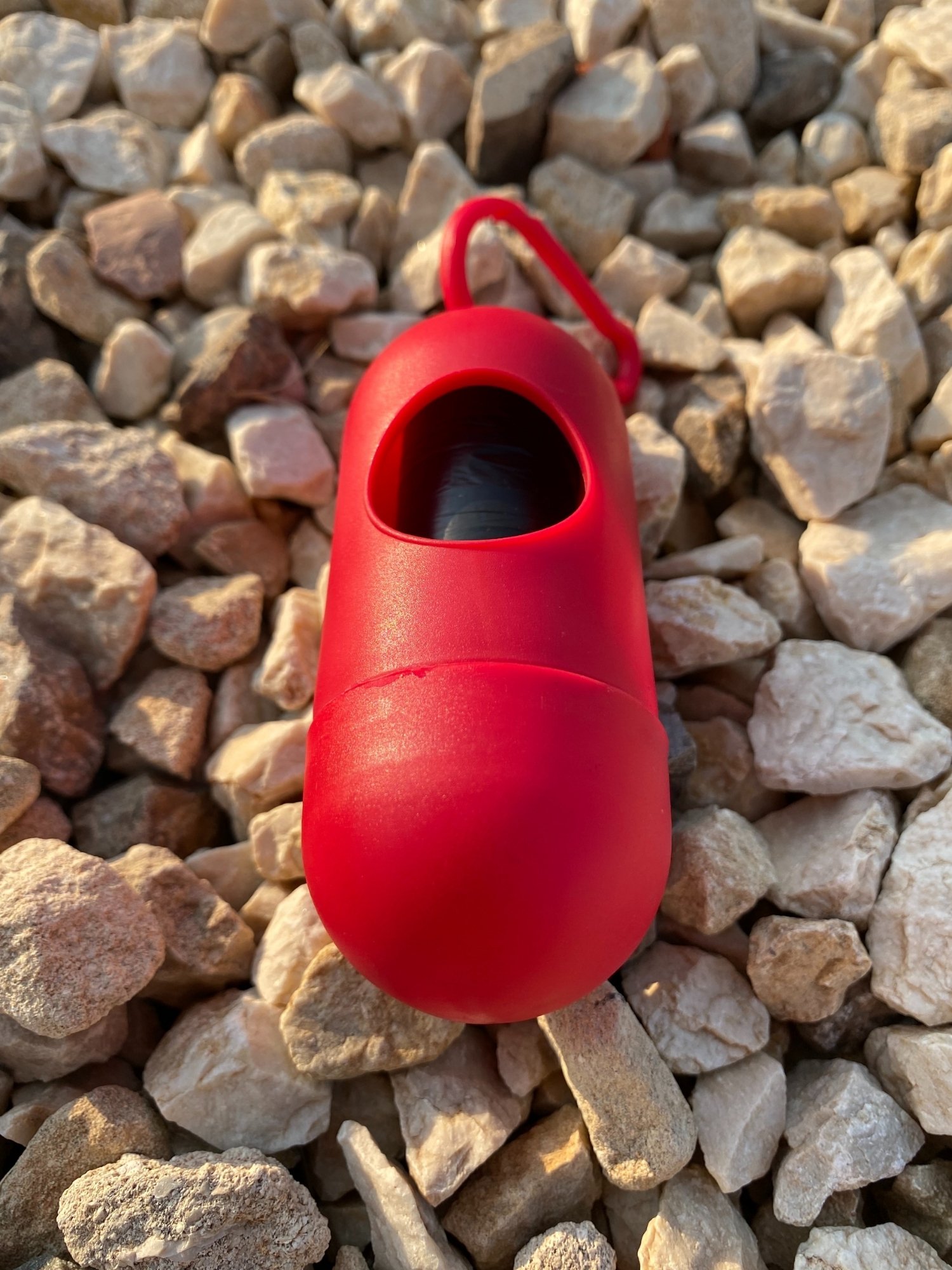 Dog Poop Bag Dispenser in Blue, Red, and Green colors with bags attached, showcasing its carabiner clip and easy-access slot.