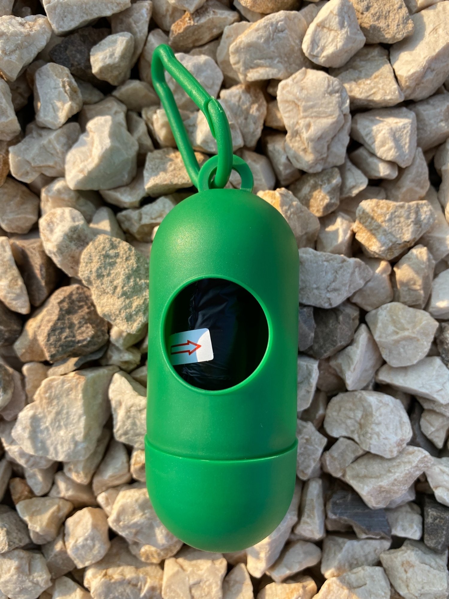 Dog Poop Bag Dispenser in Blue, Red, and Green colors with bags attached, showcasing its carabiner clip and easy-access slot.