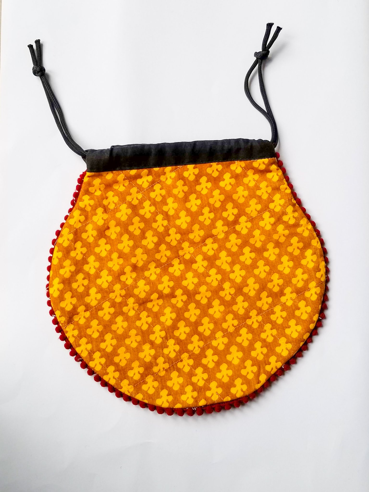 A colorful handcrafted drawstring sari pouch showcasing unique patterns and vibrant colors, perfect for storing small items.