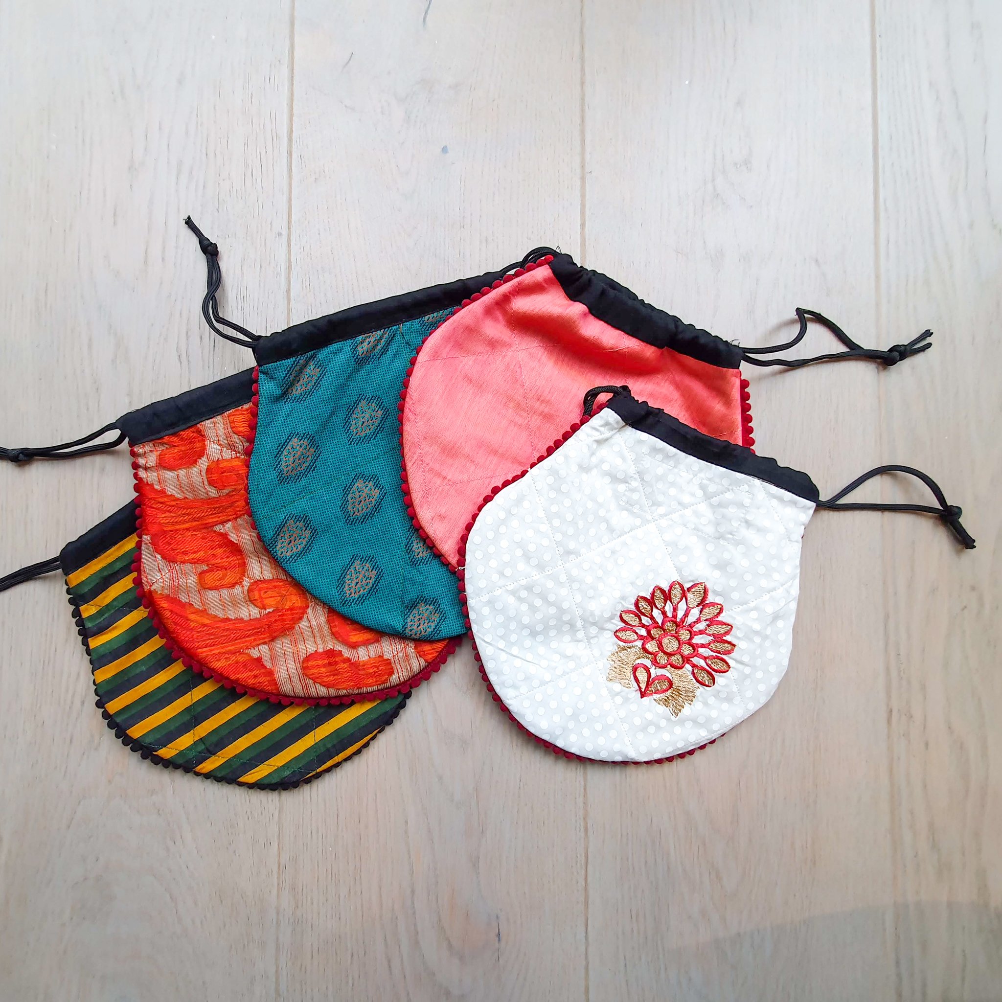 A colorful handcrafted drawstring sari pouch showcasing unique patterns and vibrant colors, perfect for storing small items.