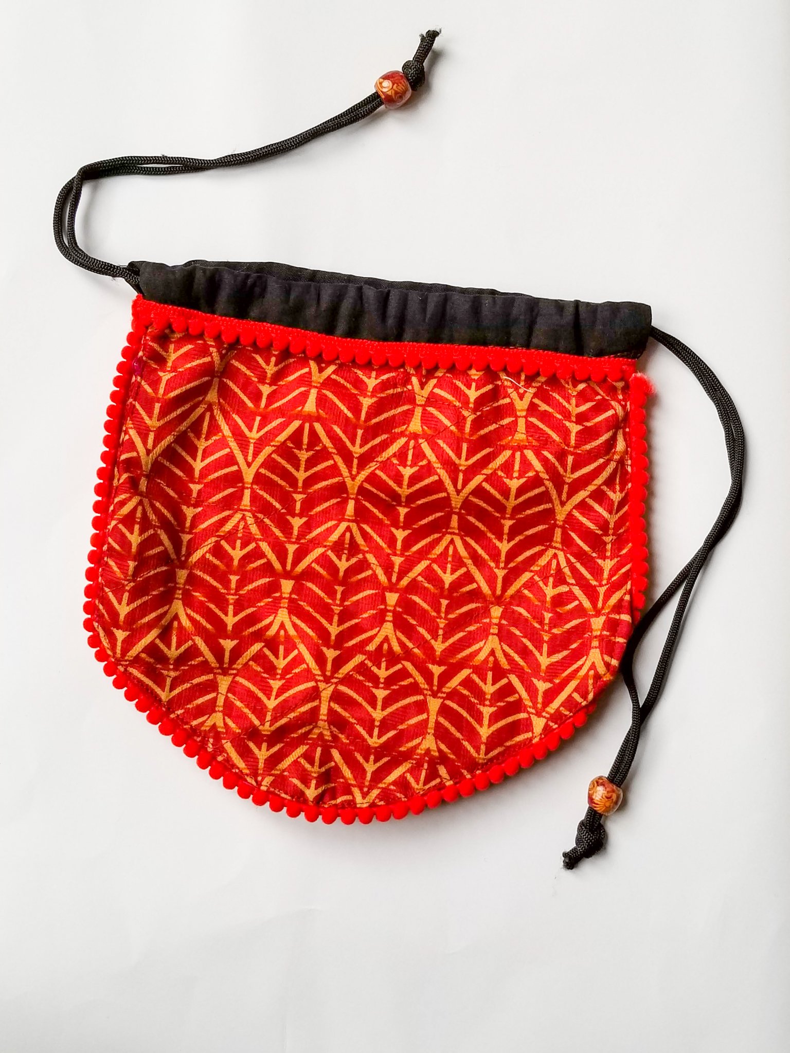 A colorful handcrafted drawstring sari pouch showcasing unique patterns and vibrant colors, perfect for storing small items.