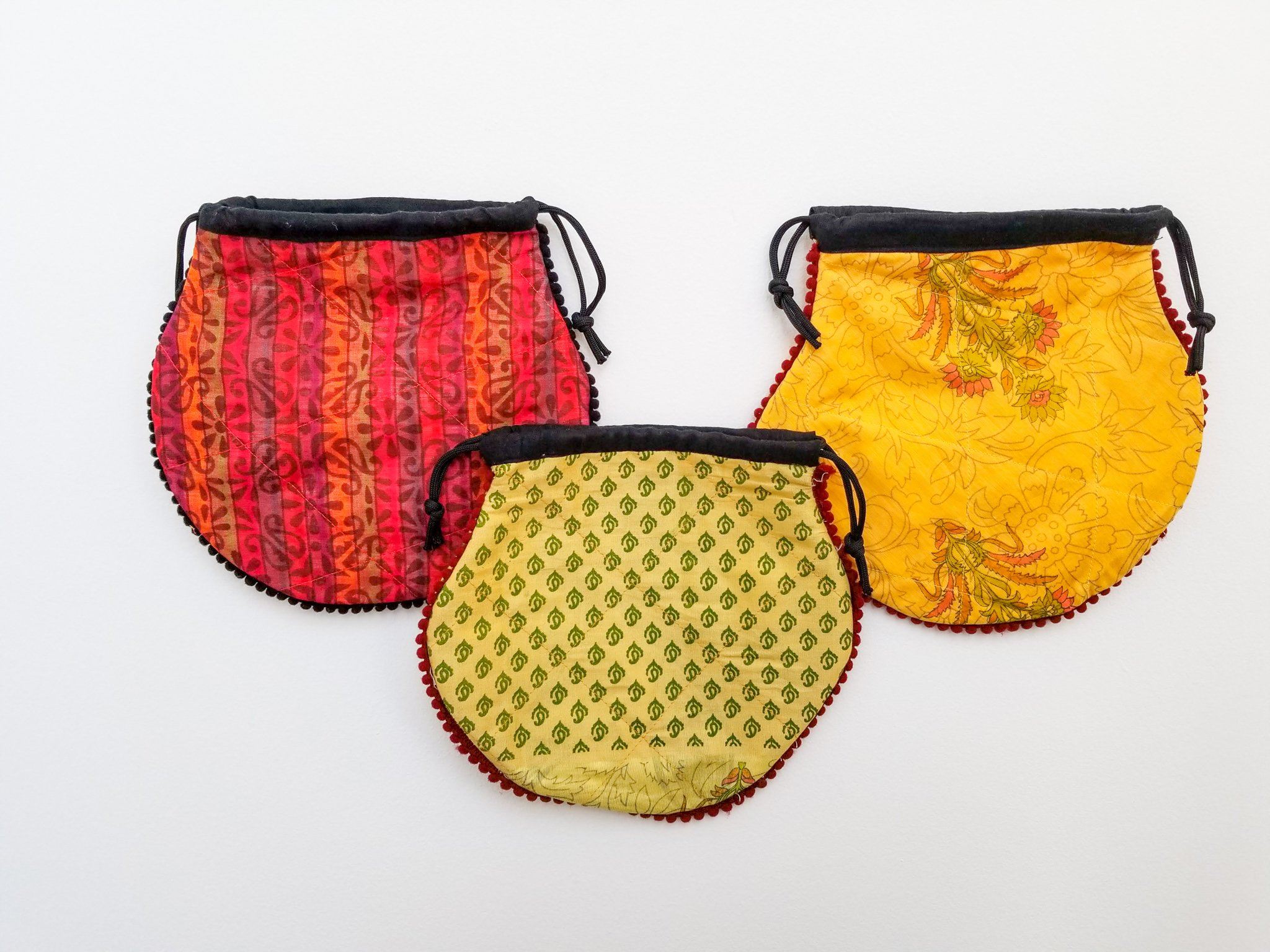 A colorful handcrafted drawstring sari pouch showcasing unique patterns and vibrant colors, perfect for storing small items.