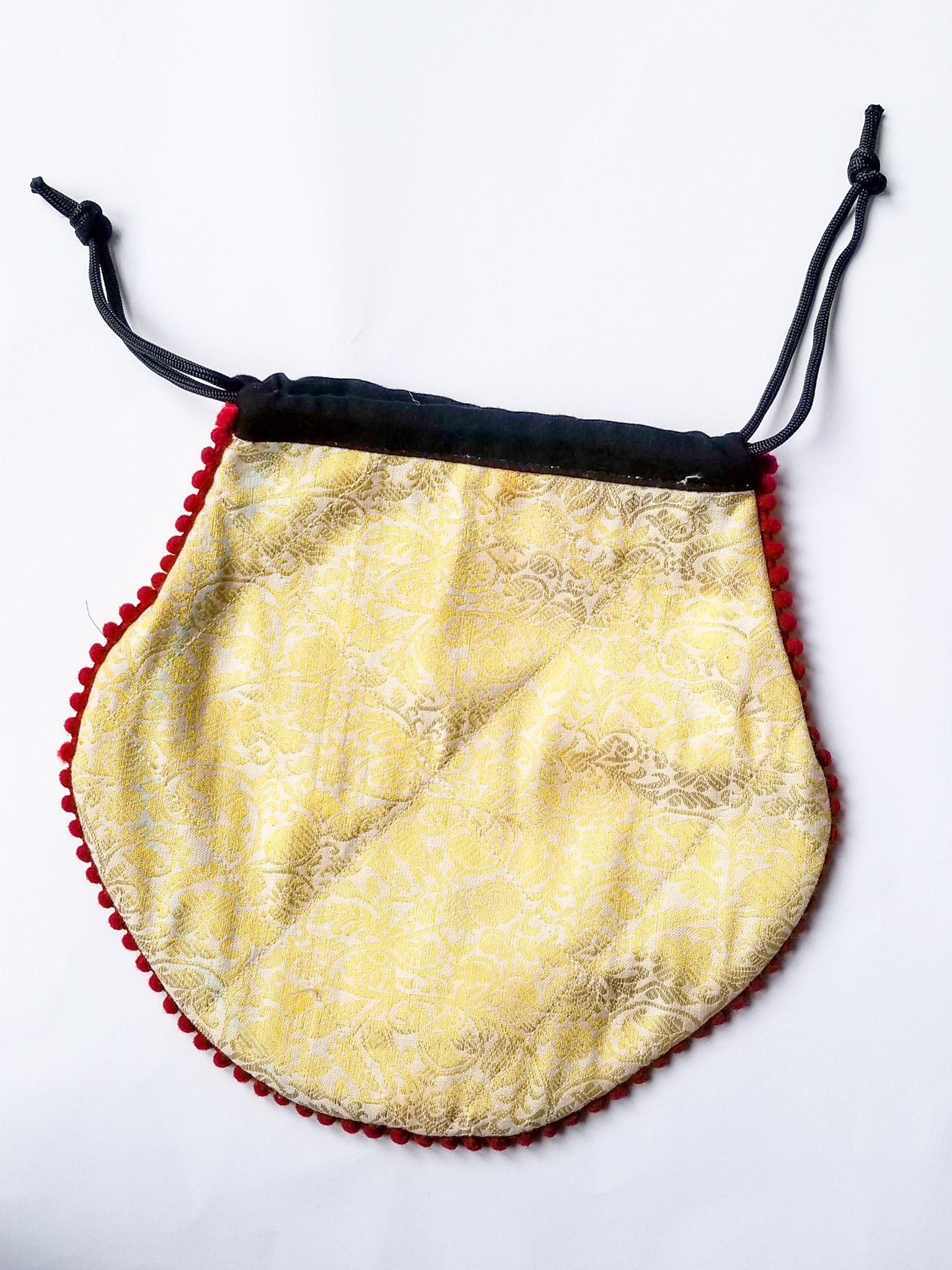 A colorful handcrafted drawstring sari pouch showcasing unique patterns and vibrant colors, perfect for storing small items.