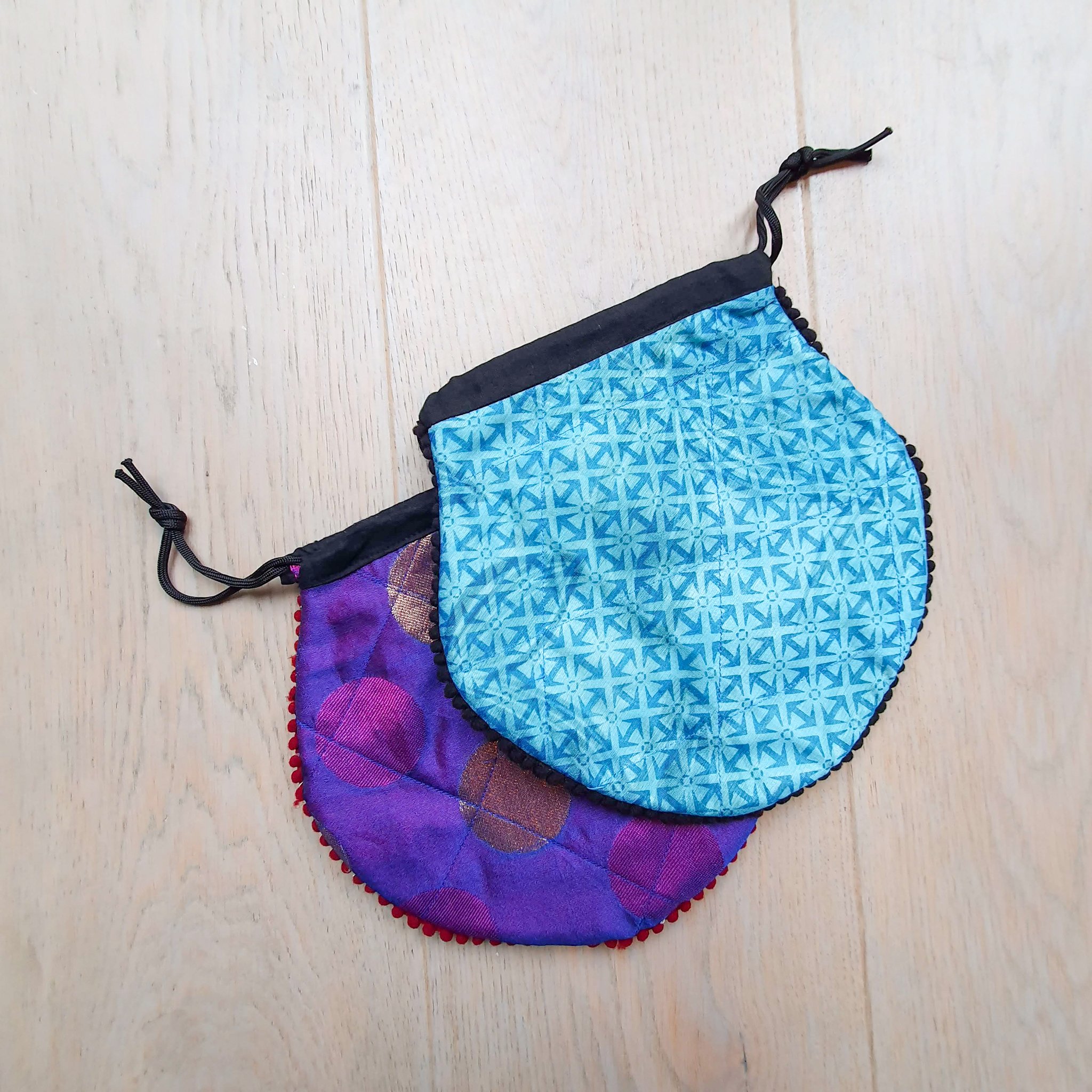 A colorful handcrafted drawstring sari pouch showcasing unique patterns and vibrant colors, perfect for storing small items.