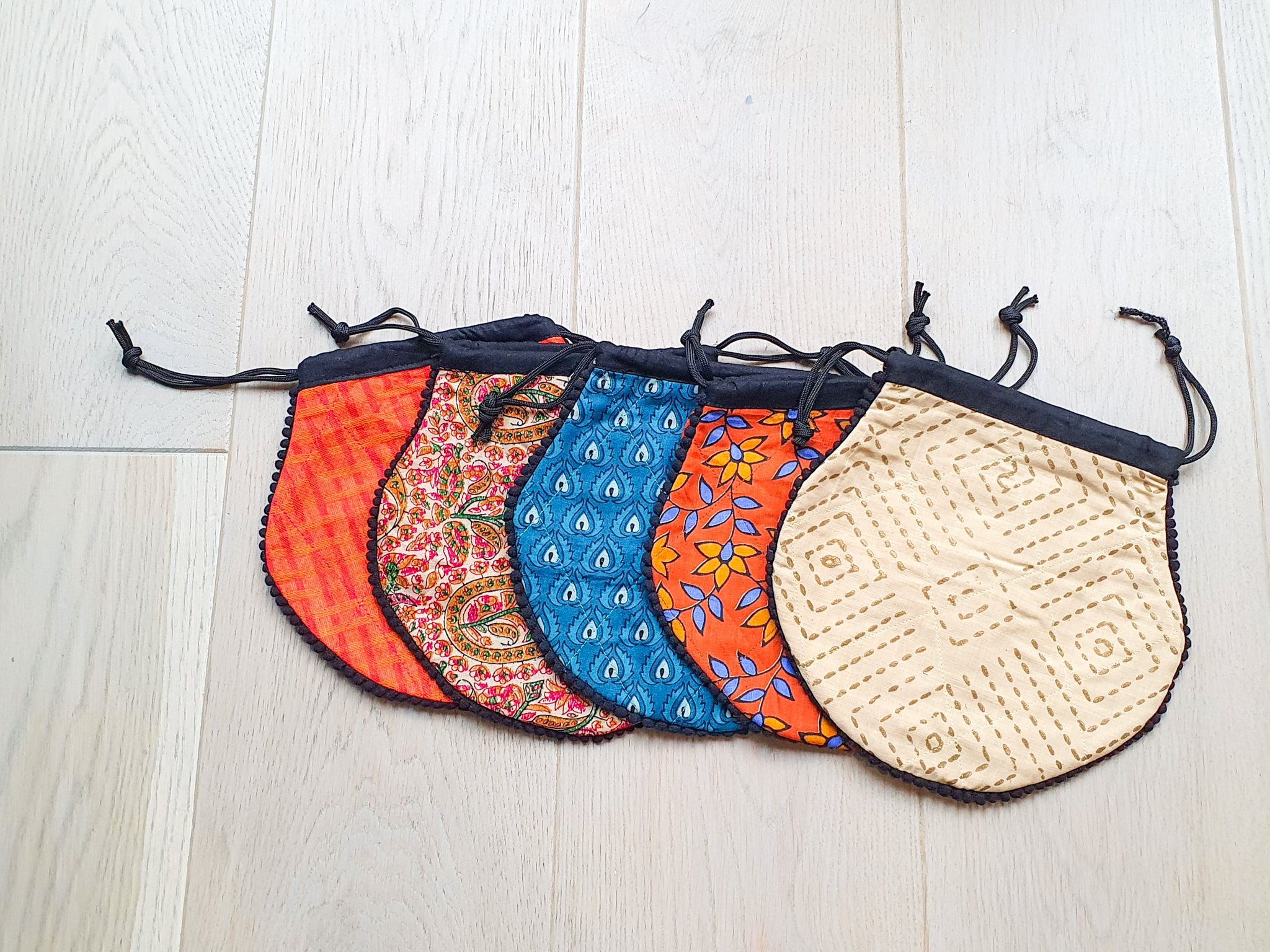 A colorful handcrafted drawstring sari pouch showcasing unique patterns and vibrant colors, perfect for storing small items.