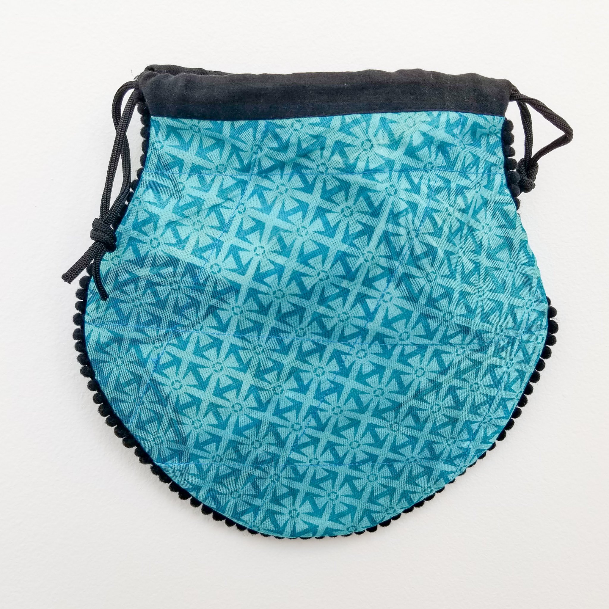 A colorful handcrafted drawstring sari pouch showcasing unique patterns and vibrant colors, perfect for storing small items.