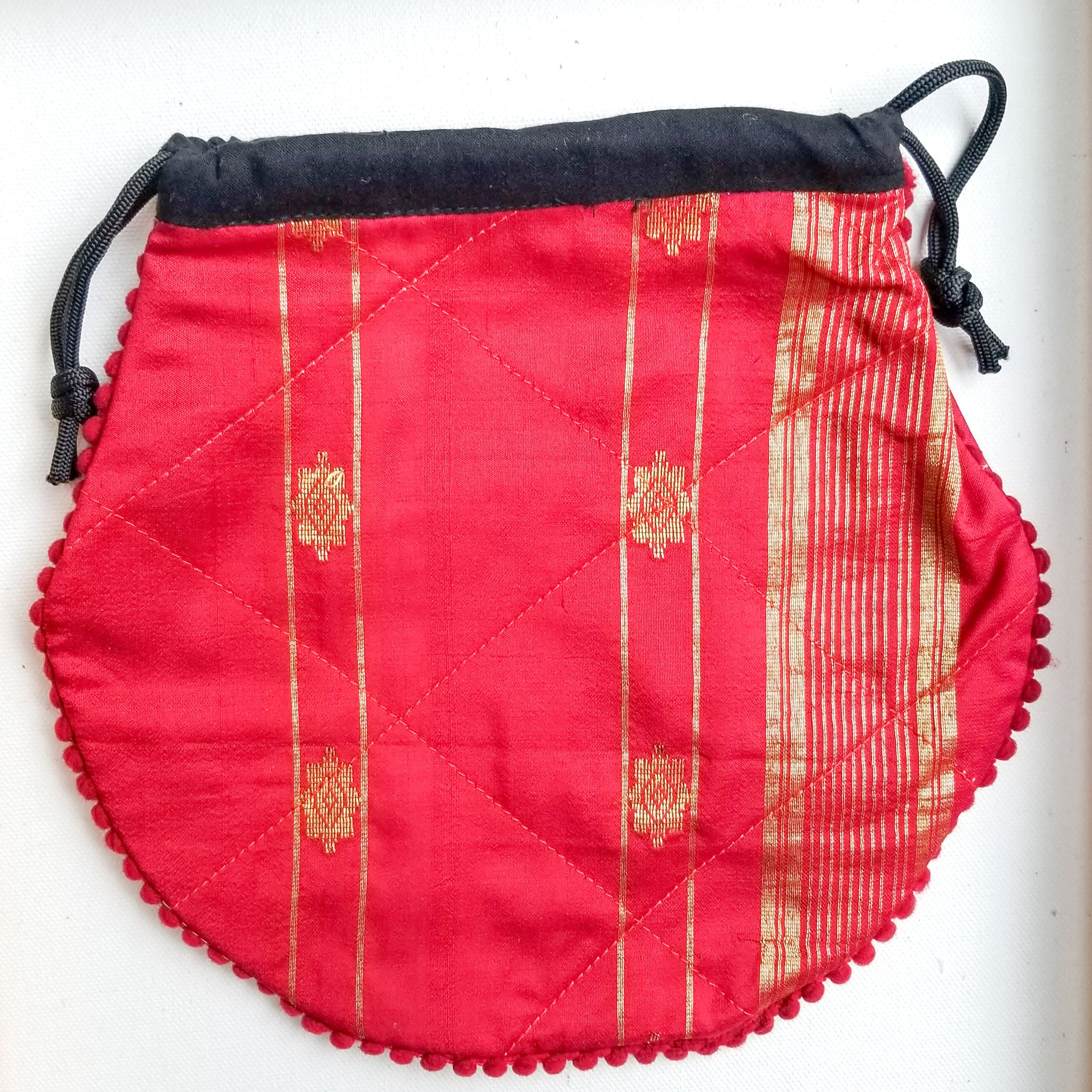 A colorful handcrafted drawstring sari pouch showcasing unique patterns and vibrant colors, perfect for storing small items.