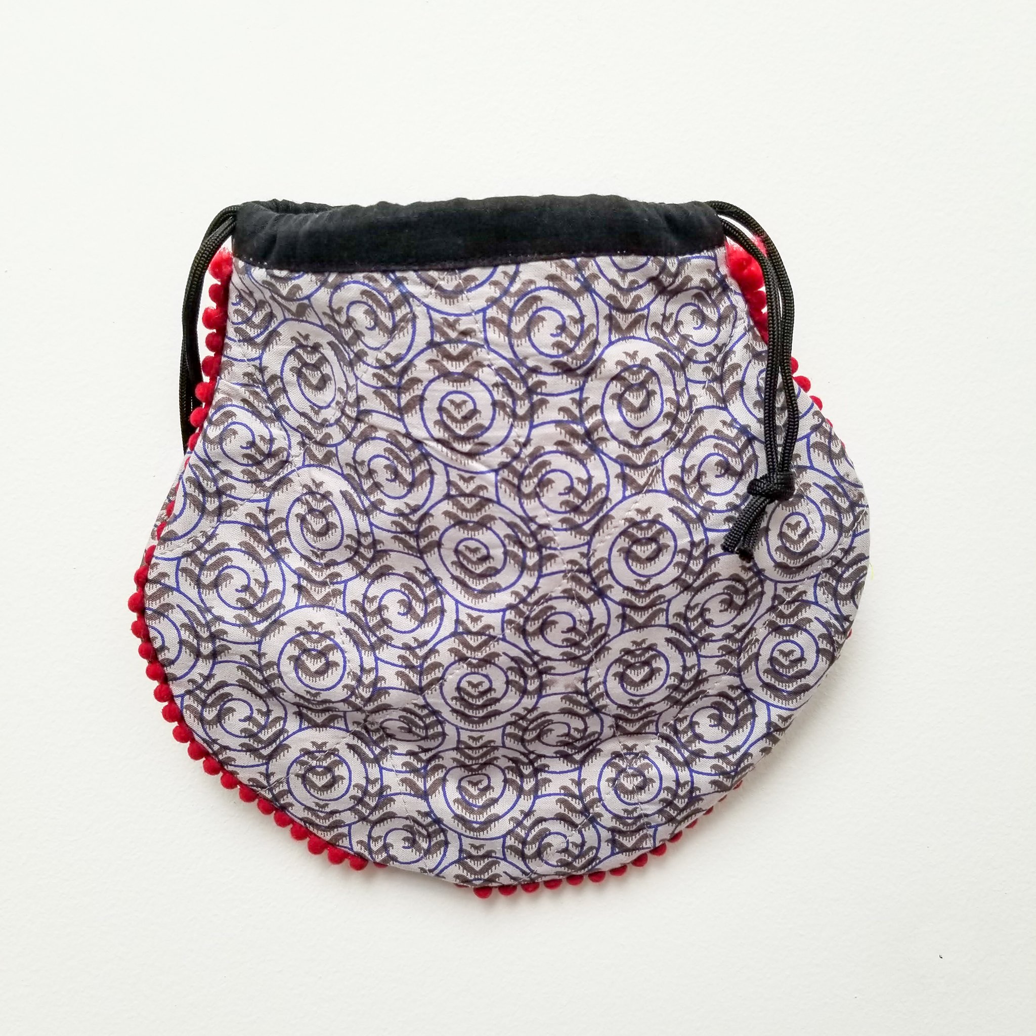 A colorful handcrafted drawstring sari pouch showcasing unique patterns and vibrant colors, perfect for storing small items.