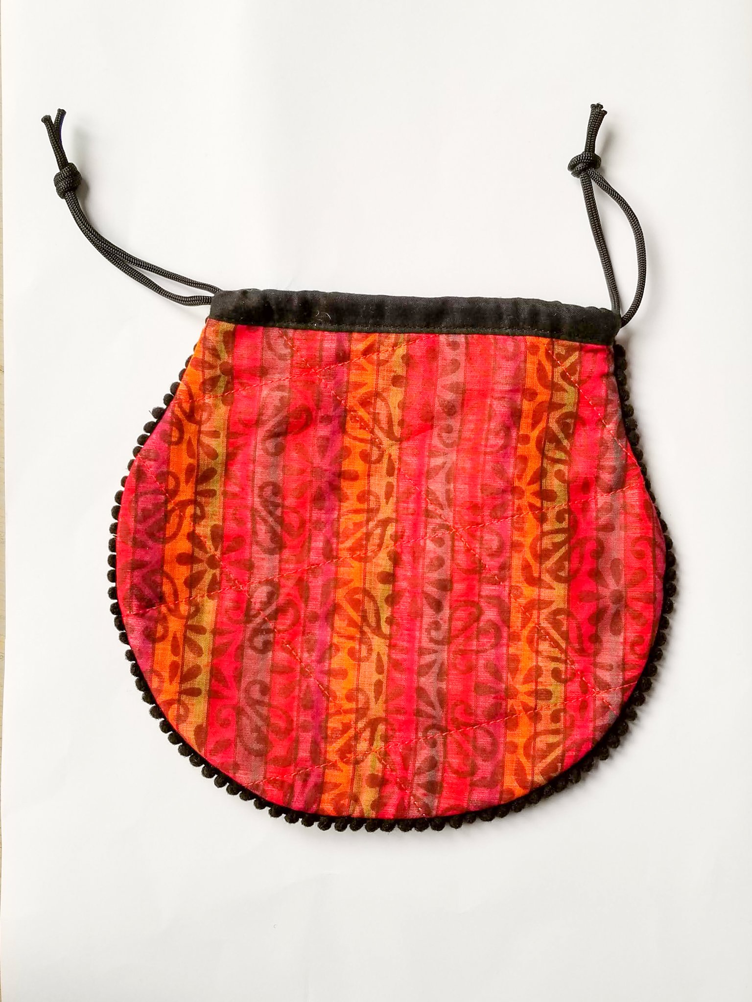 A colorful handcrafted drawstring sari pouch showcasing unique patterns and vibrant colors, perfect for storing small items.