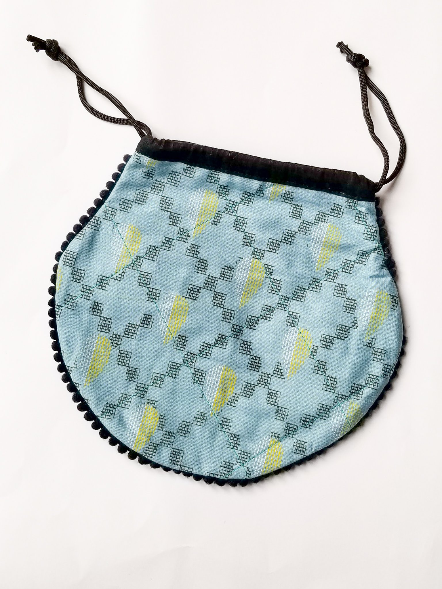 A colorful handcrafted drawstring sari pouch showcasing unique patterns and vibrant colors, perfect for storing small items.