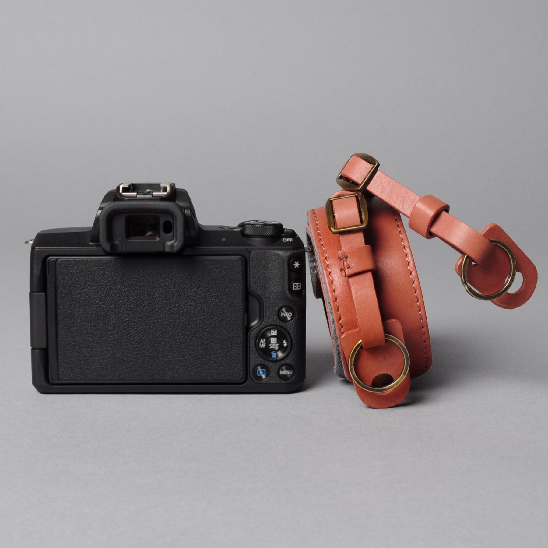 A stylish DSLR camera leather strap made from durable harness leather with antique brass hardware, showcasing its adjustable length and metal rings.