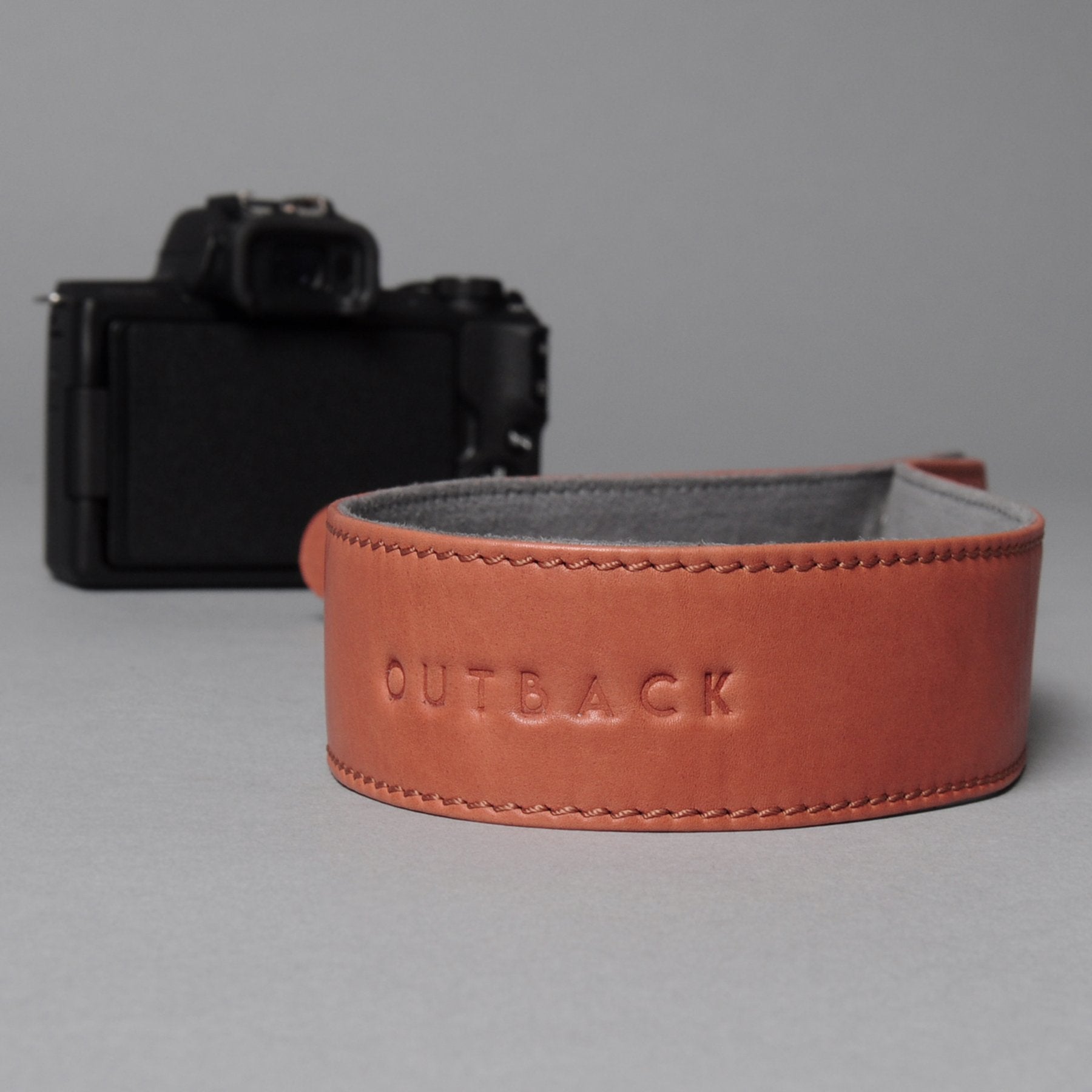 A stylish DSLR camera leather strap made from durable harness leather with antique brass hardware, showcasing its adjustable length and metal rings.