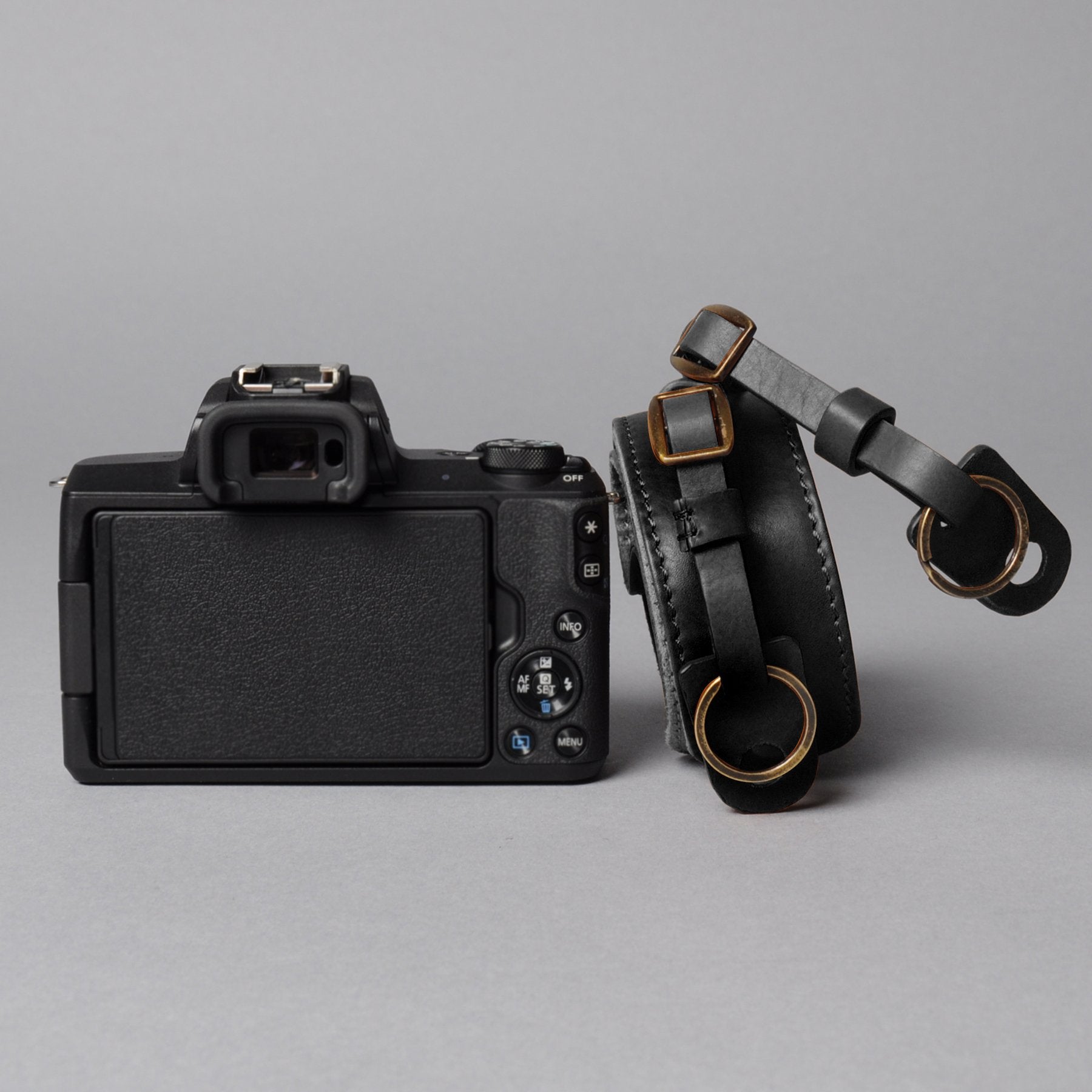 A stylish DSLR camera leather strap made from durable harness leather with antique brass hardware, showcasing its adjustable length and metal rings.