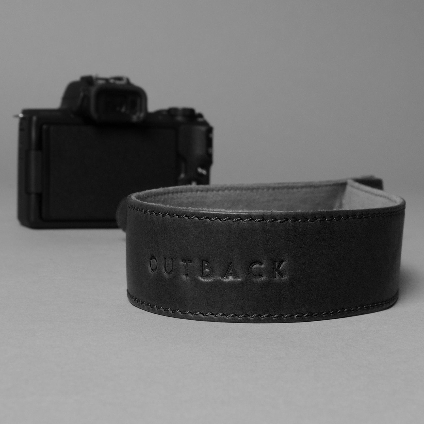 A stylish DSLR camera leather strap made from durable harness leather with antique brass hardware, showcasing its adjustable length and metal rings.