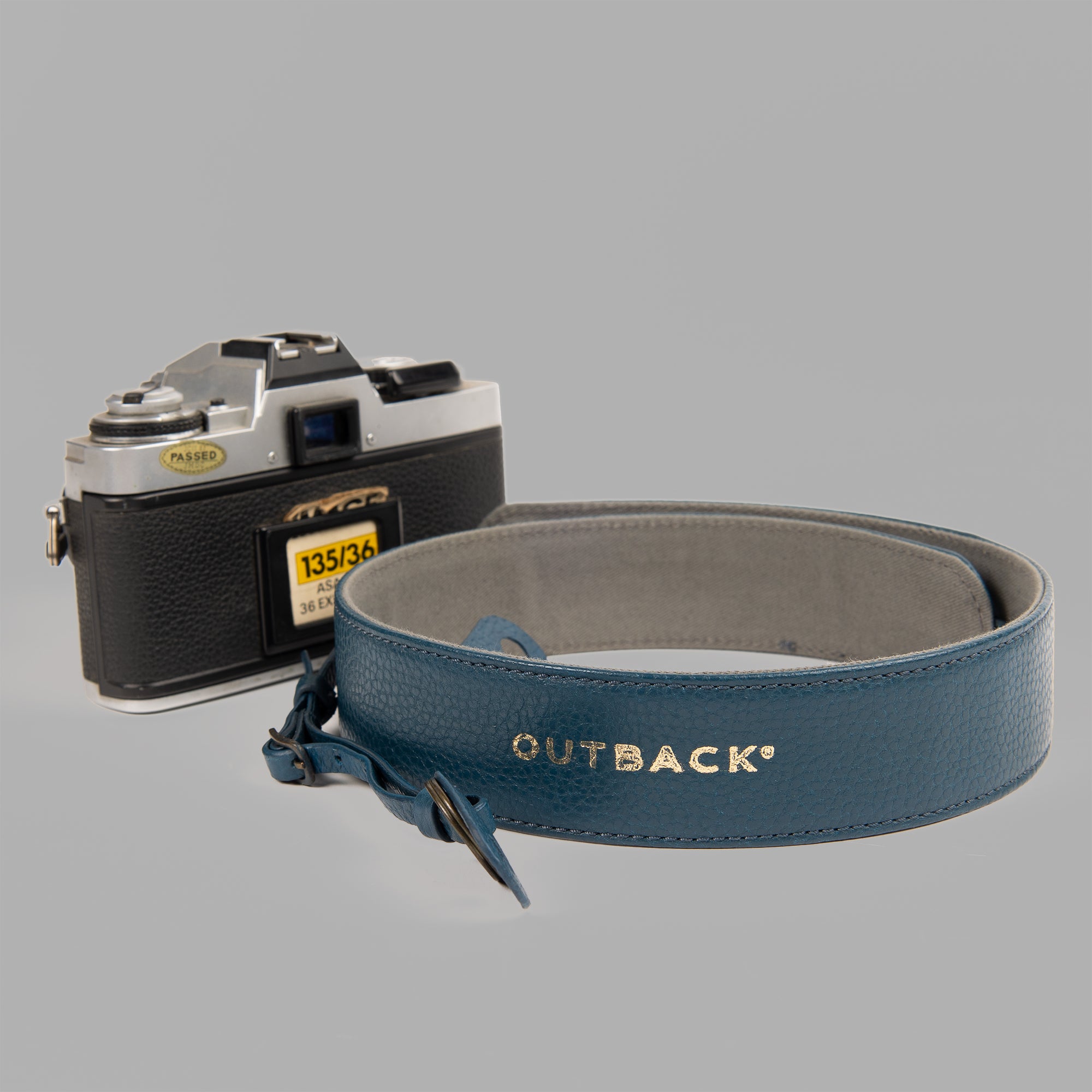 A stylish DSLR camera leather strap made from durable harness leather with antique brass hardware, showcasing its adjustable length and metal rings.