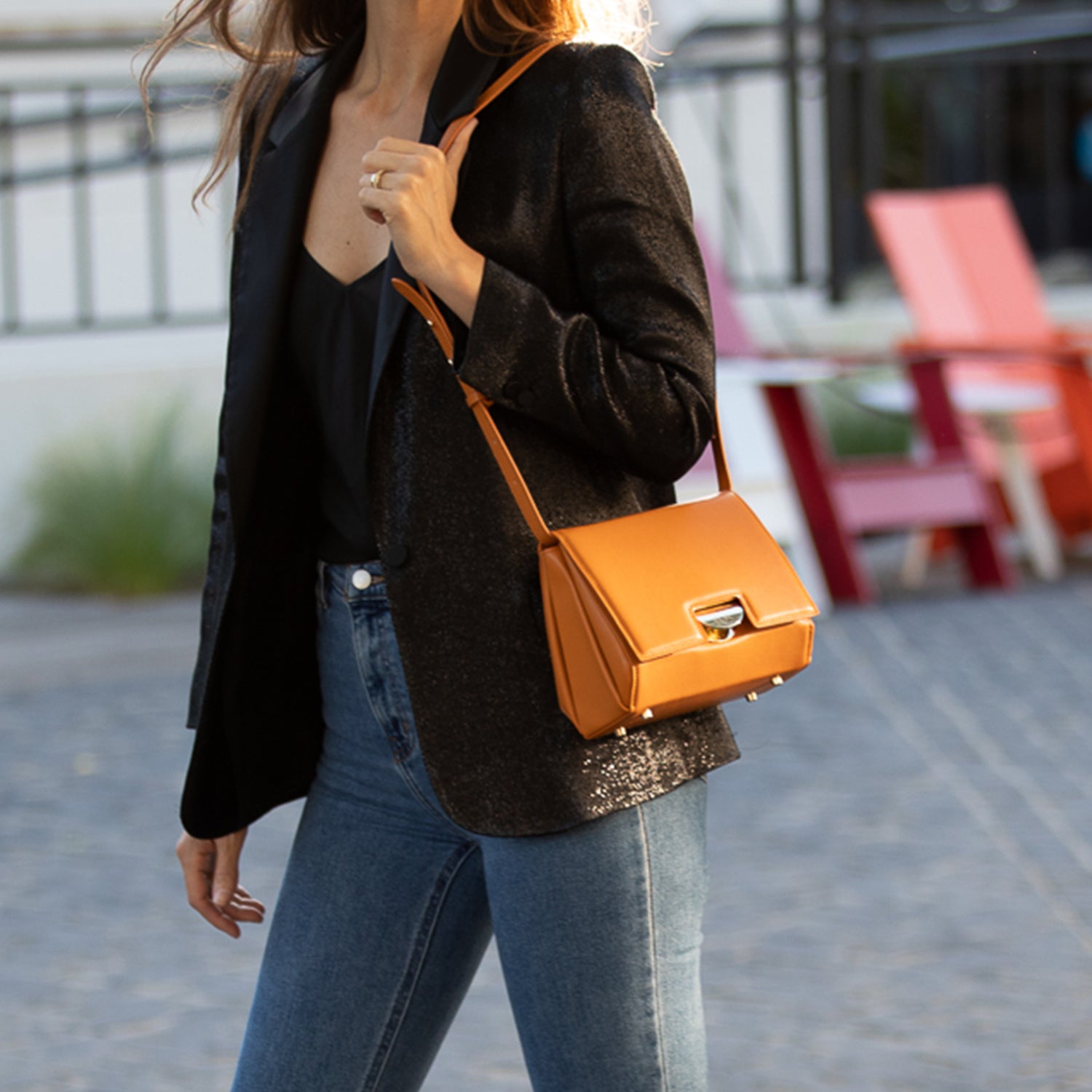 Elizabeth Dark Orange Leather Saddle Bag with gold hardware and adjustable strap, showcasing its geometric shape and teal interior.