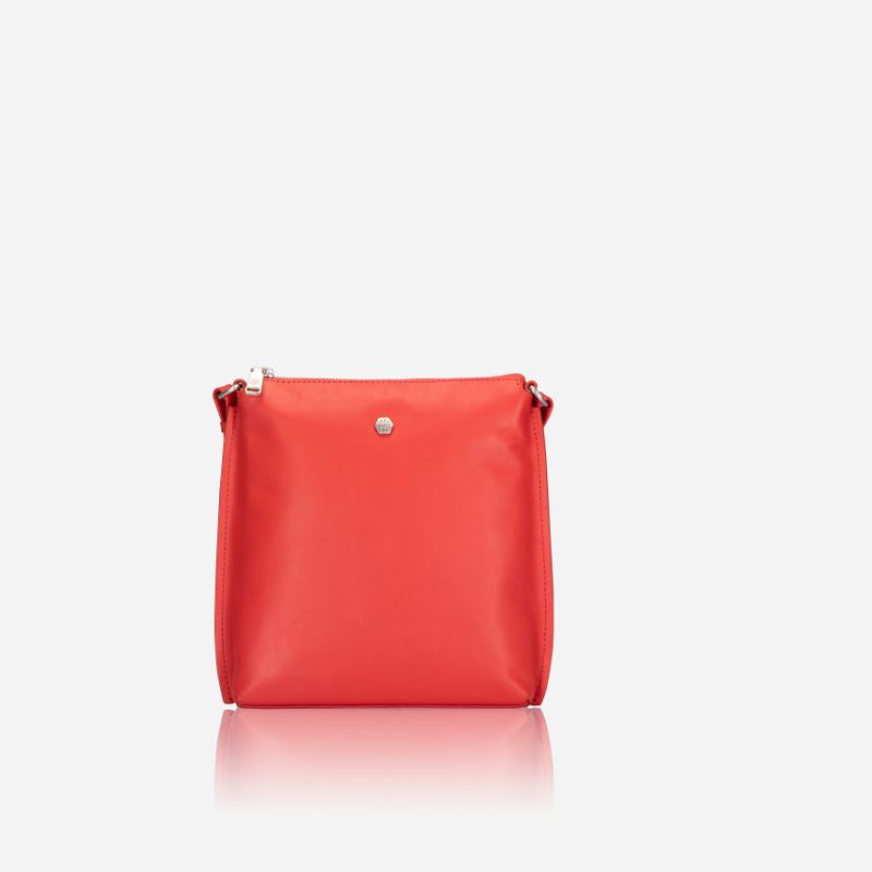 Essentials Crossbody bag in vibrant Candy Apple leather, showcasing its stylish design and adjustable strap.