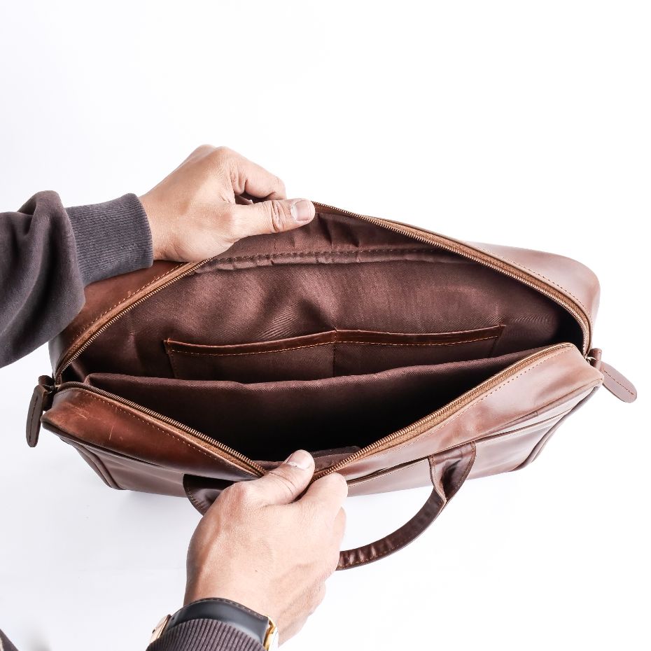 Tan brown leather laptop bag with vintage two-tone design, featuring adjustable shoulder strap and multiple compartments.