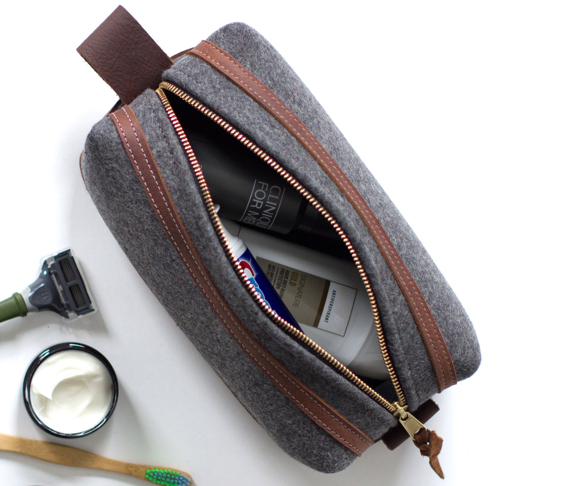 Stylish felt and leather toiletry bag with brass zippers and water-resistant liner, showcasing its unique design and personalization option.