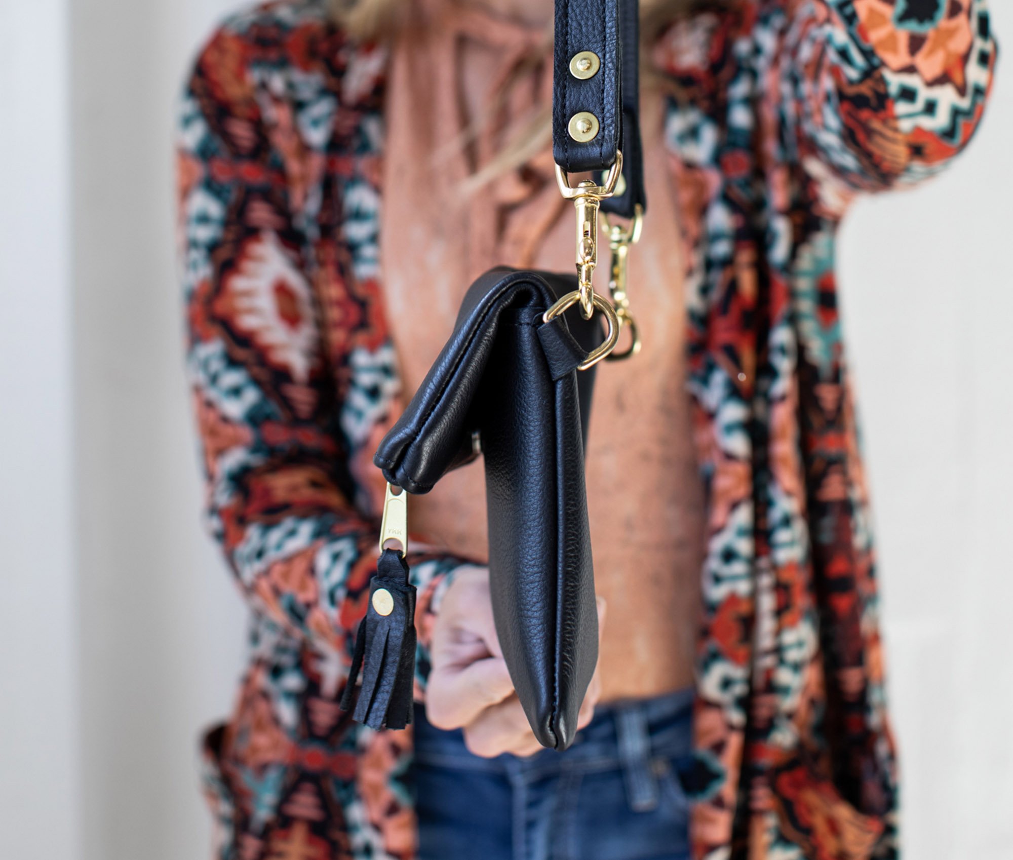 A stylish Foldover Crossbody Clutch made from genuine full grain leather, featuring adjustable straps and a foldover design with a zipper and magnetic snap pocket.