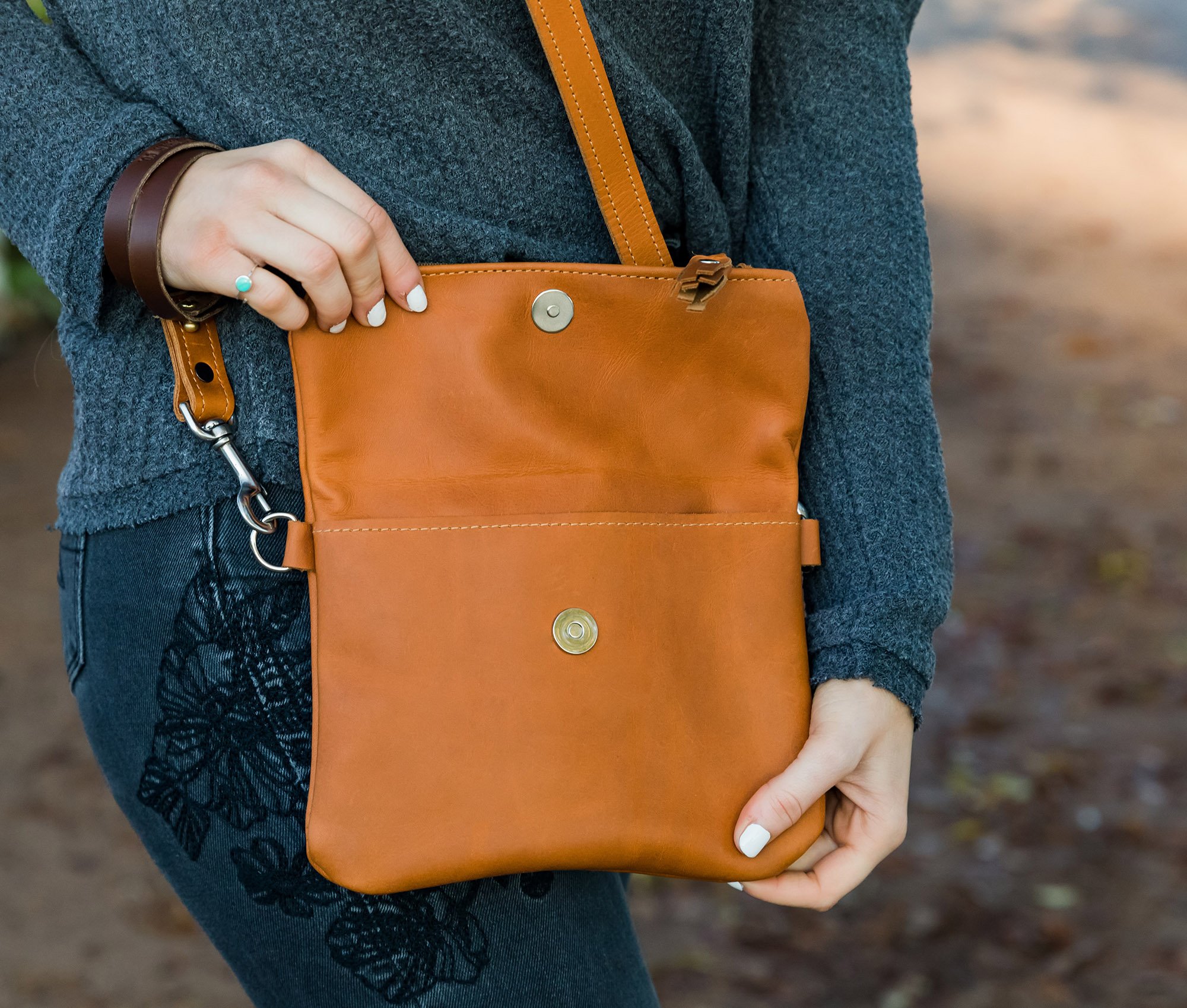 A stylish Foldover Crossbody Clutch made from genuine full grain leather, featuring adjustable straps and a foldover design with a zipper and magnetic snap pocket.