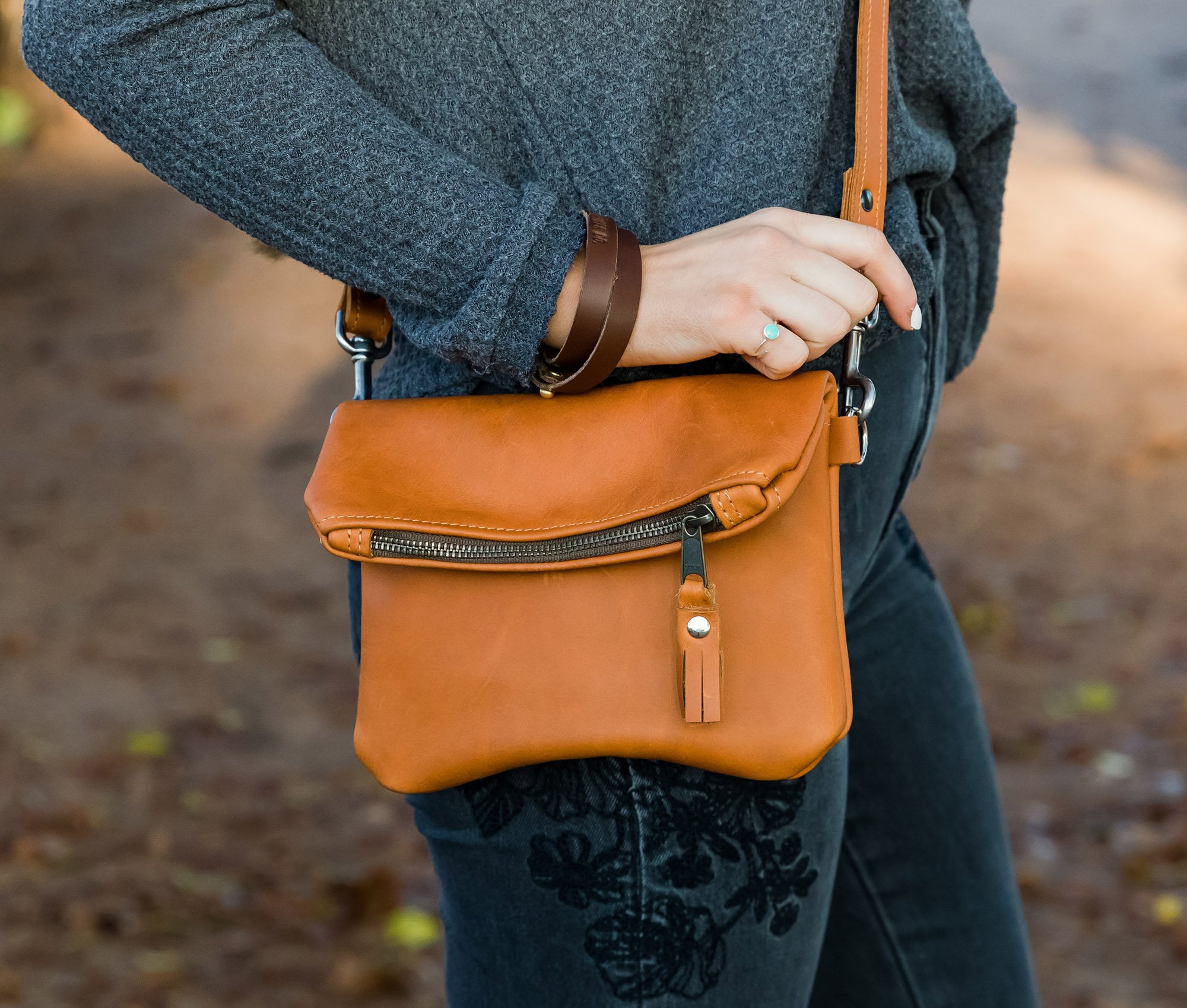 A stylish Foldover Crossbody Clutch made from genuine full grain leather, featuring adjustable straps and a foldover design with a zipper and magnetic snap pocket.