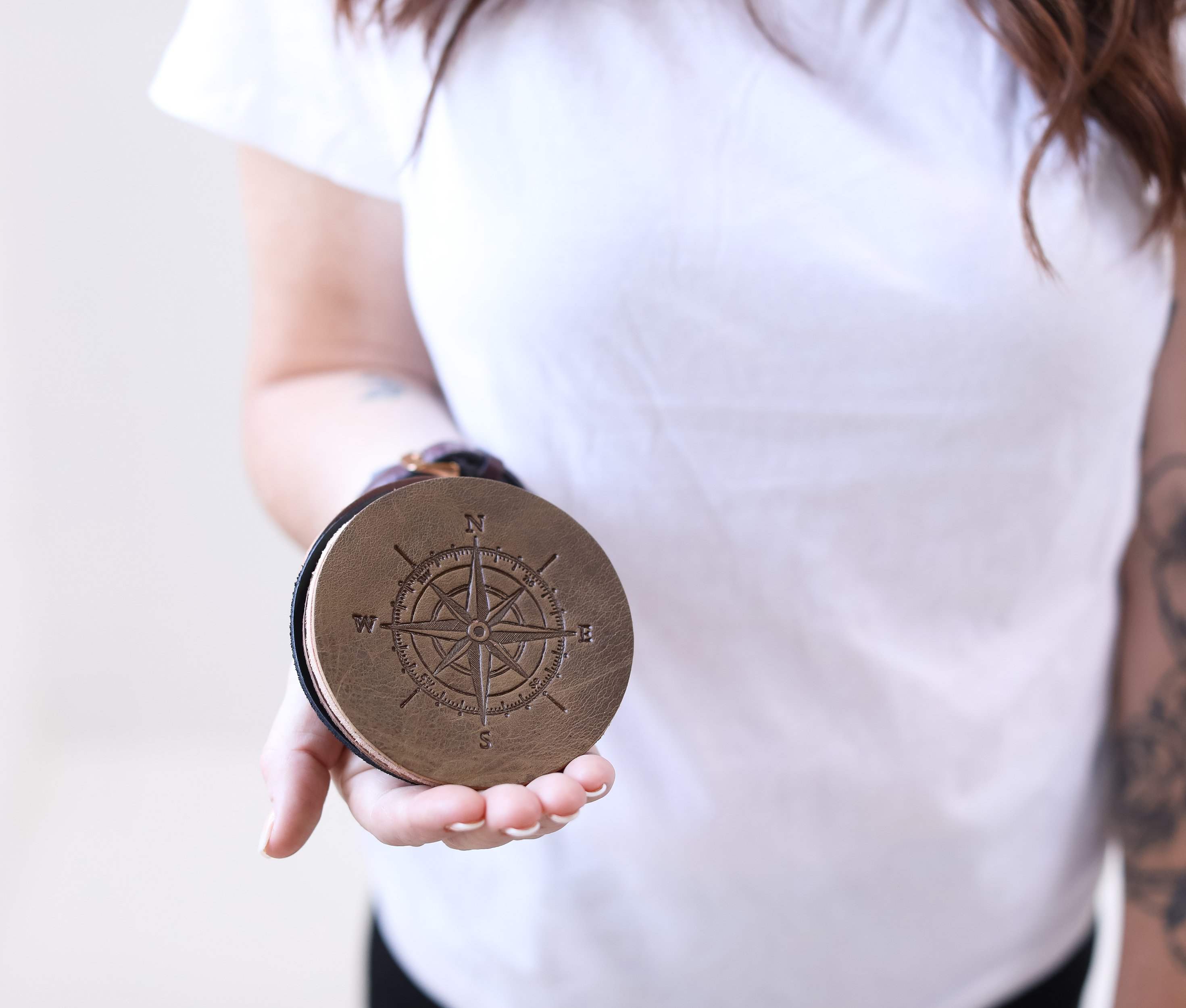 A set of four genuine leather coasters in various colors, showcasing personalization options with initials and fire branded designs.