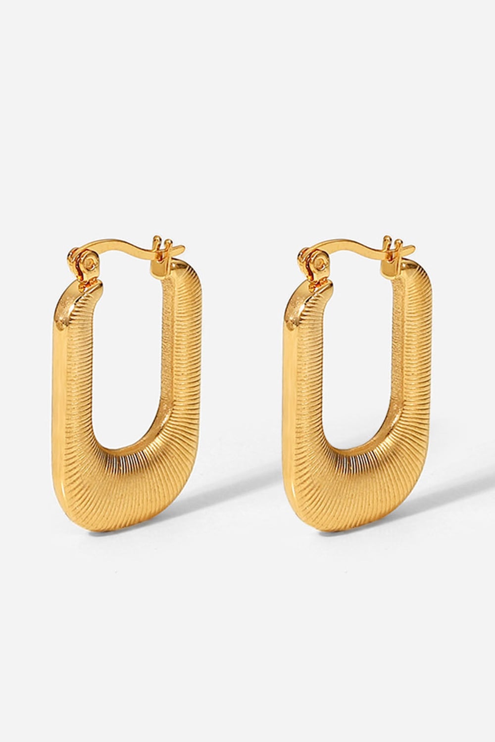 A pair of gold-plated U-shaped earrings with a chunky design and subtle screw-thread texture, showcasing elegance and sophistication.