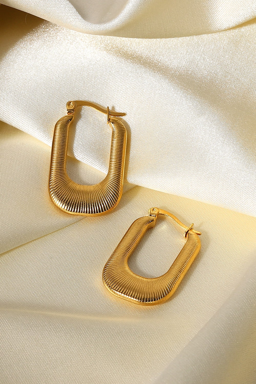 A pair of gold-plated U-shaped earrings with a chunky design and subtle screw-thread texture, showcasing elegance and sophistication.