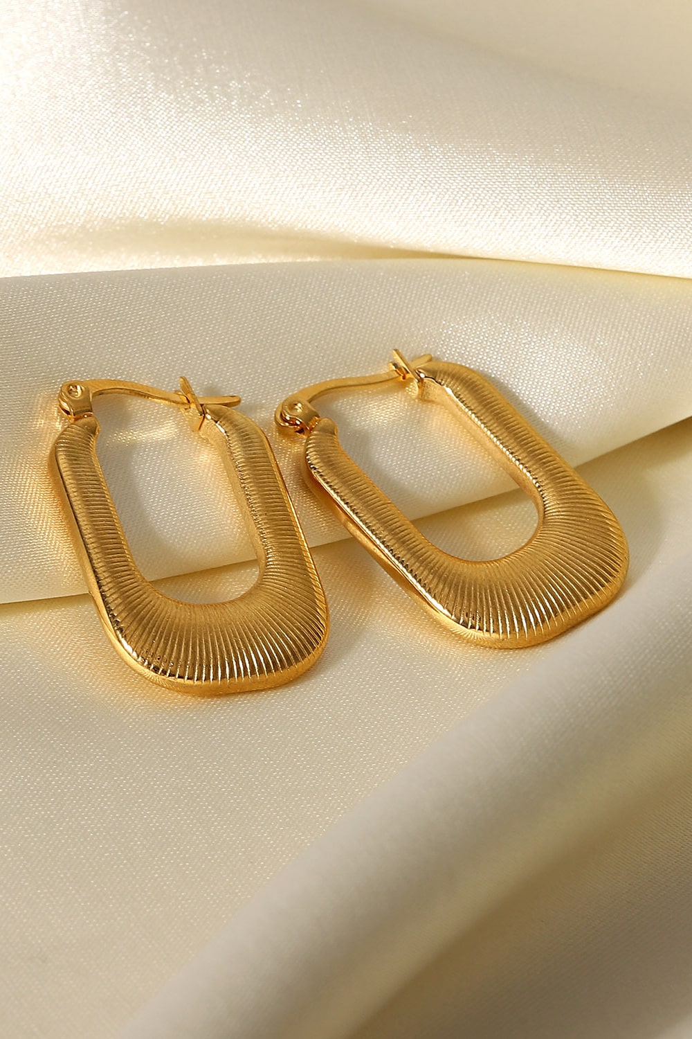 A pair of gold-plated U-shaped earrings with a chunky design and subtle screw-thread texture, showcasing elegance and sophistication.