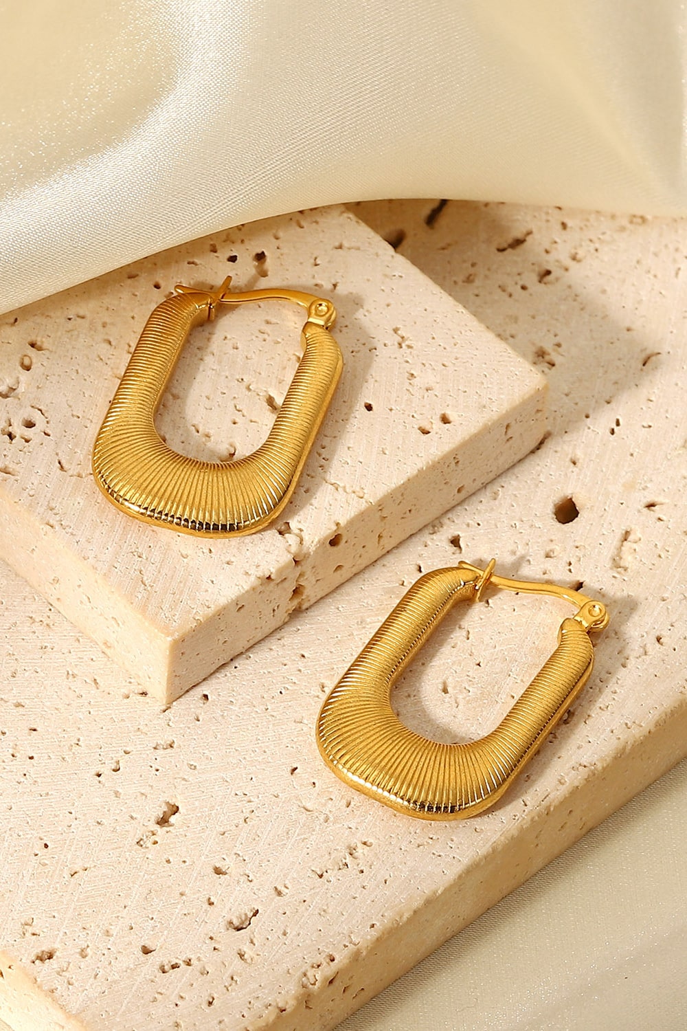 A pair of gold-plated U-shaped earrings with a chunky design and subtle screw-thread texture, showcasing elegance and sophistication.