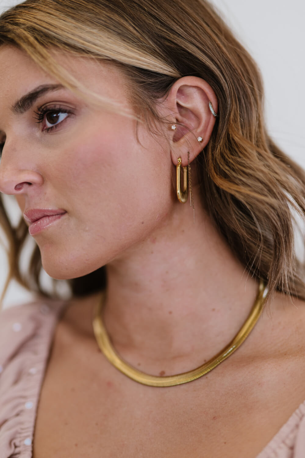 A pair of gold-plated U-shaped earrings with a chunky design and subtle screw-thread texture, showcasing elegance and sophistication.