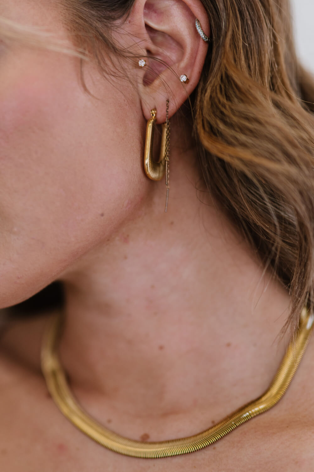 A pair of gold-plated U-shaped earrings with a chunky design and subtle screw-thread texture, showcasing elegance and sophistication.