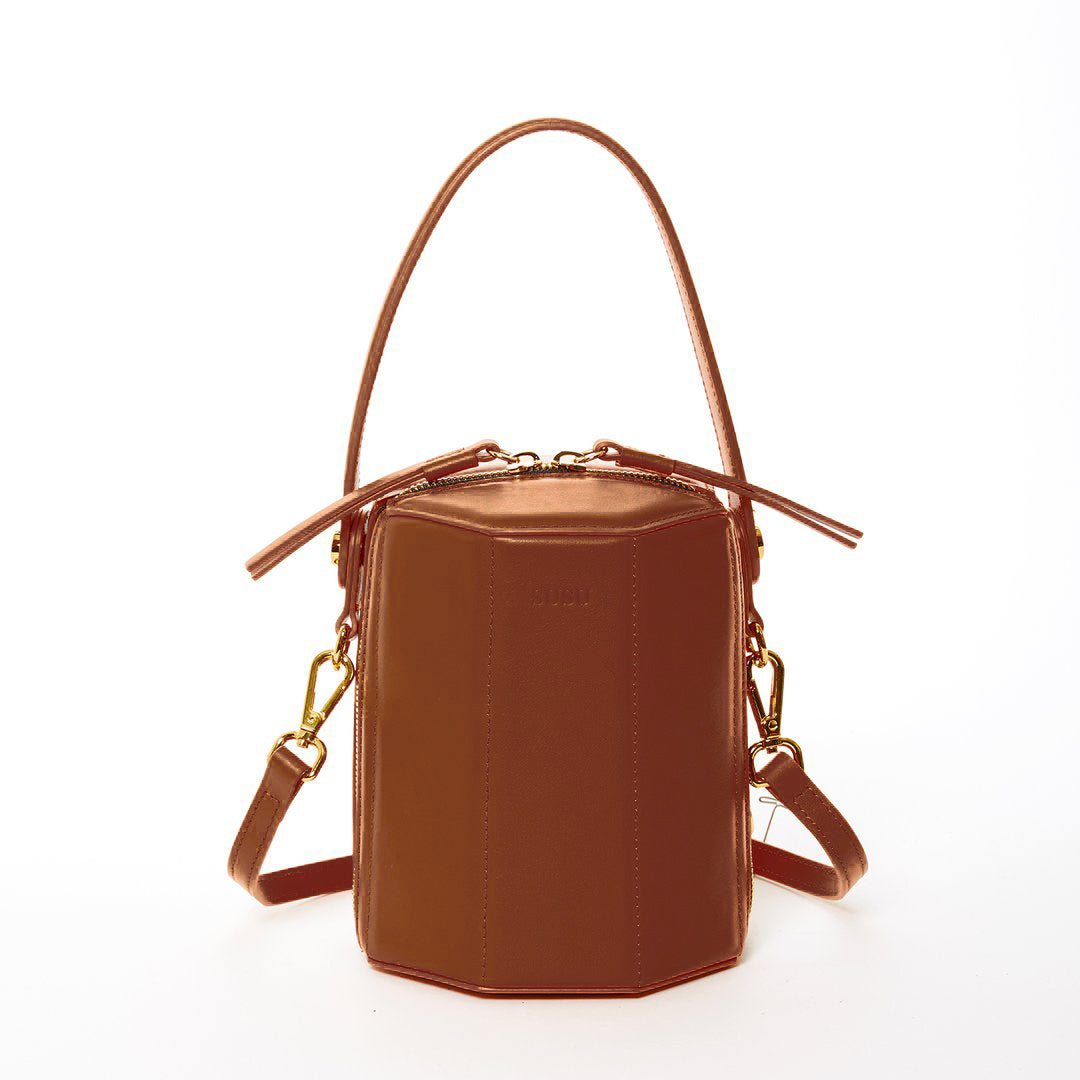 Harper Amber Brown Leather Bucket Bag featuring gold hardware and a unique geometric shape, perfect for stylish outings.