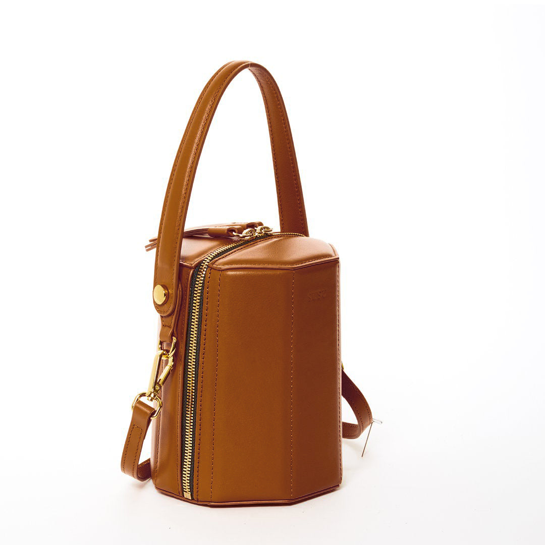 Harper Amber Brown Leather Bucket Bag featuring gold hardware and a unique geometric shape, perfect for stylish outings.