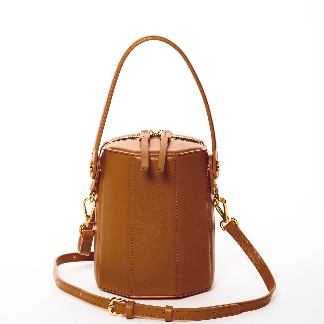 Harper Amber Brown Leather Bucket Bag featuring gold hardware and a unique geometric shape, perfect for stylish outings.