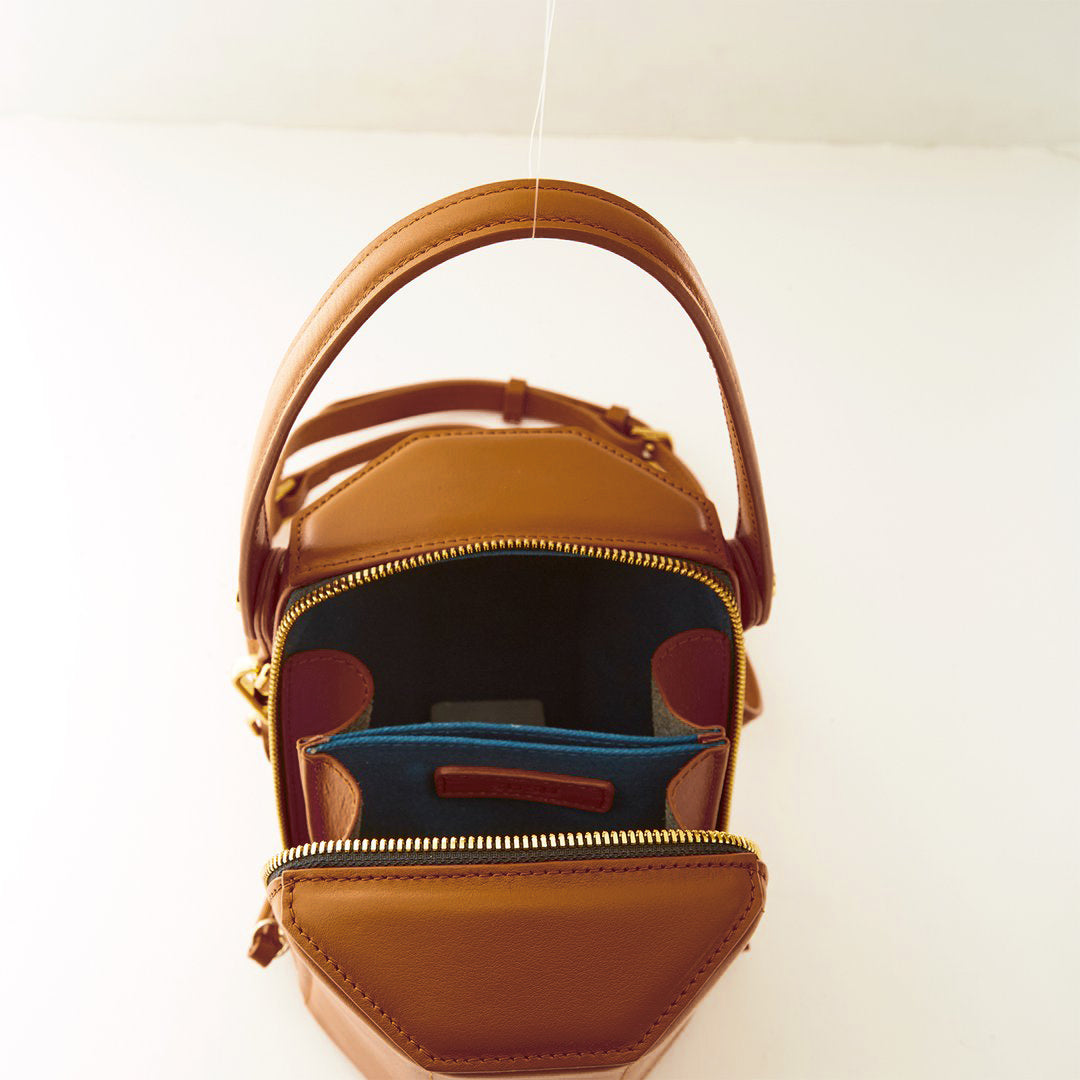 Harper Amber Brown Leather Bucket Bag featuring gold hardware and a unique geometric shape, perfect for stylish outings.