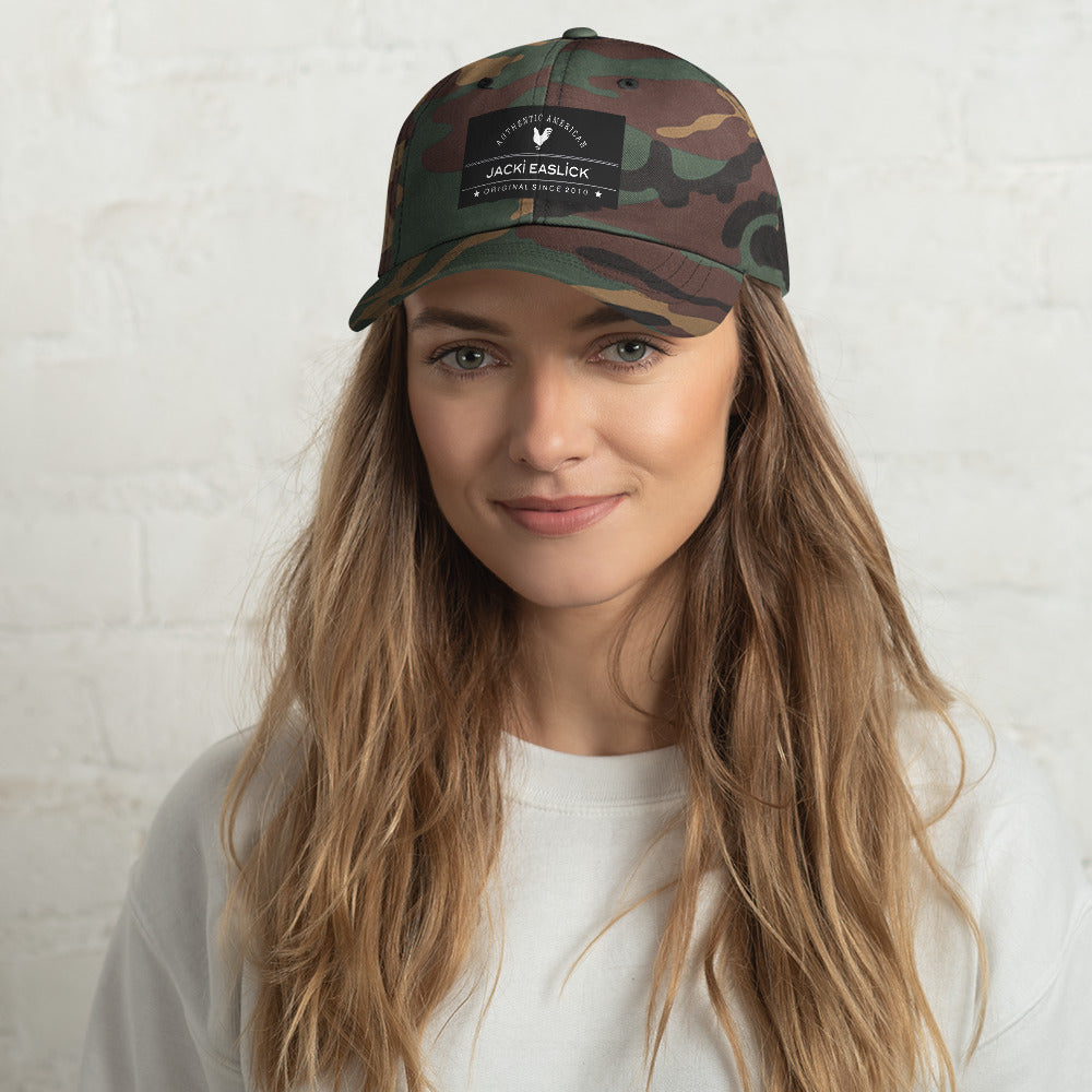 Jacki Easlick Embroidered Logo Hat in Green Camo with adjustable strap and curved visor, showcasing embroidered eyelets.