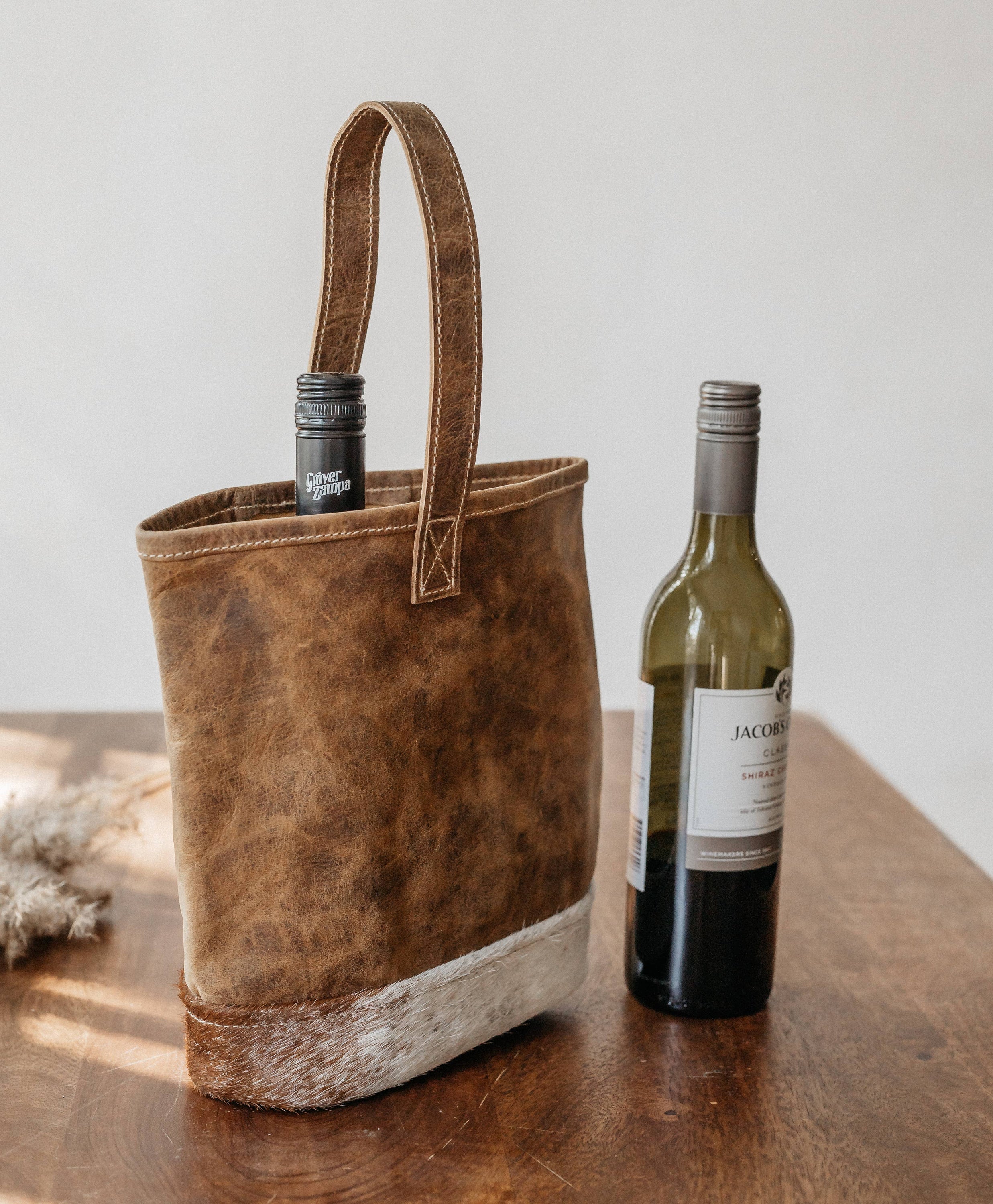 Handmade leather bottle cover with hairon material and strong handle, showcasing unique craftsmanship.