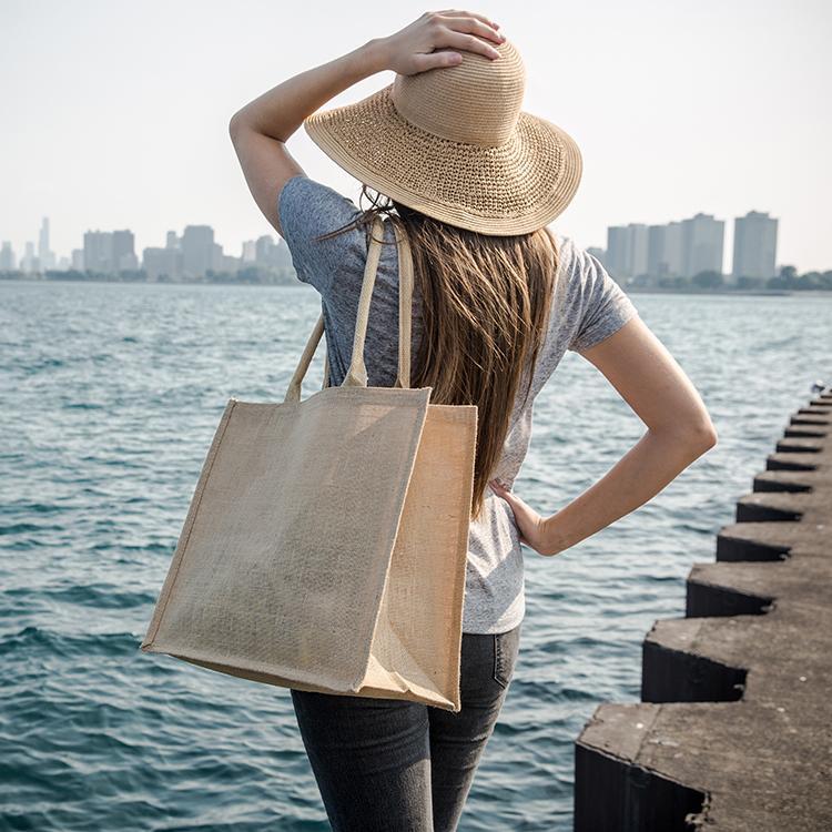 A stylish jute market bag with long handles, showcasing its rustic design and laminated interior.